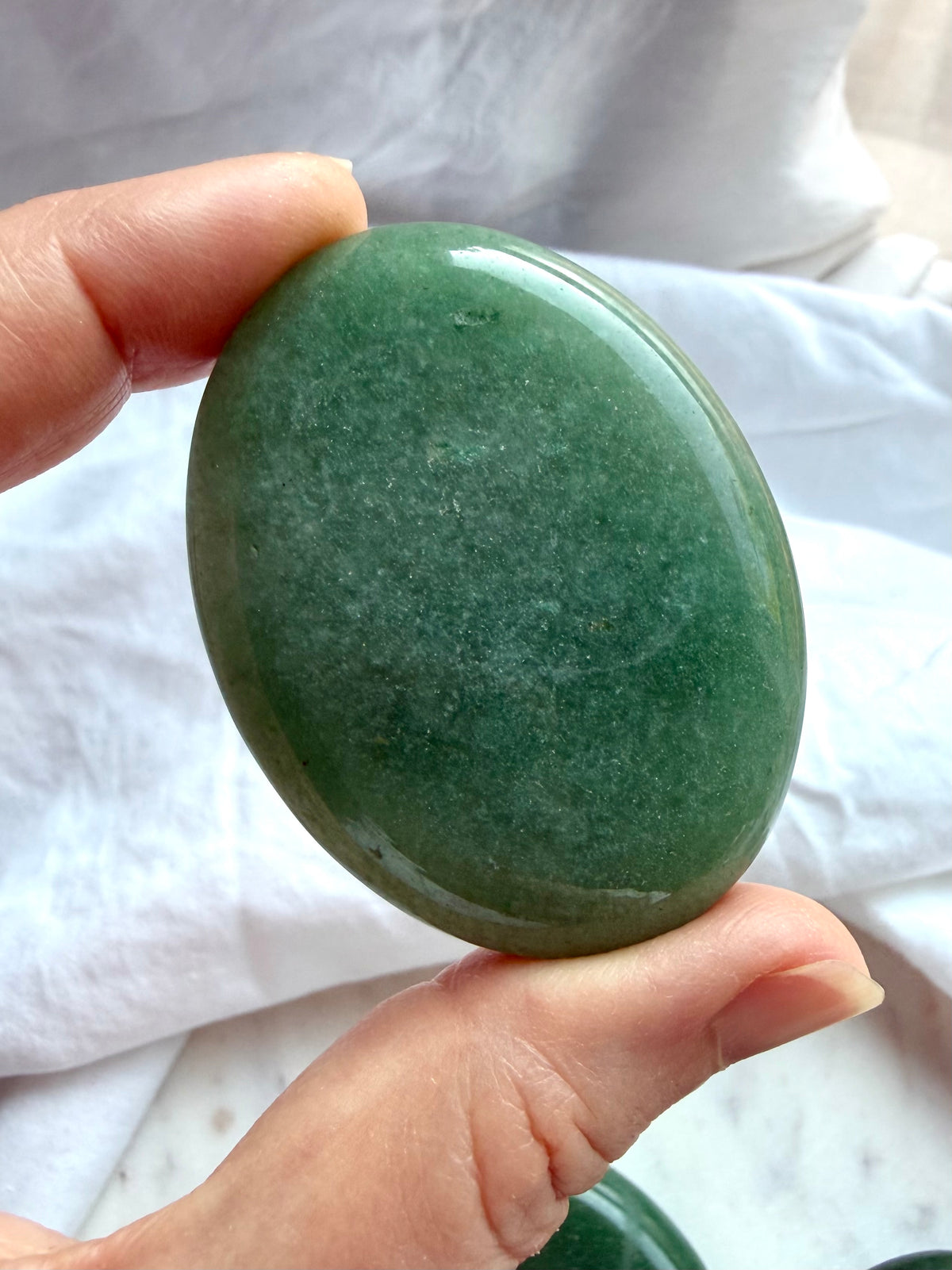 Green Aventurine palm stone held in hand showing glossy polish, green color, and delicate aventurescence