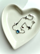 Dainty sterling silver aquamarine butterfly bracelet with heart chakra energy, styled in heart-shaped dish for gift-ready presentation