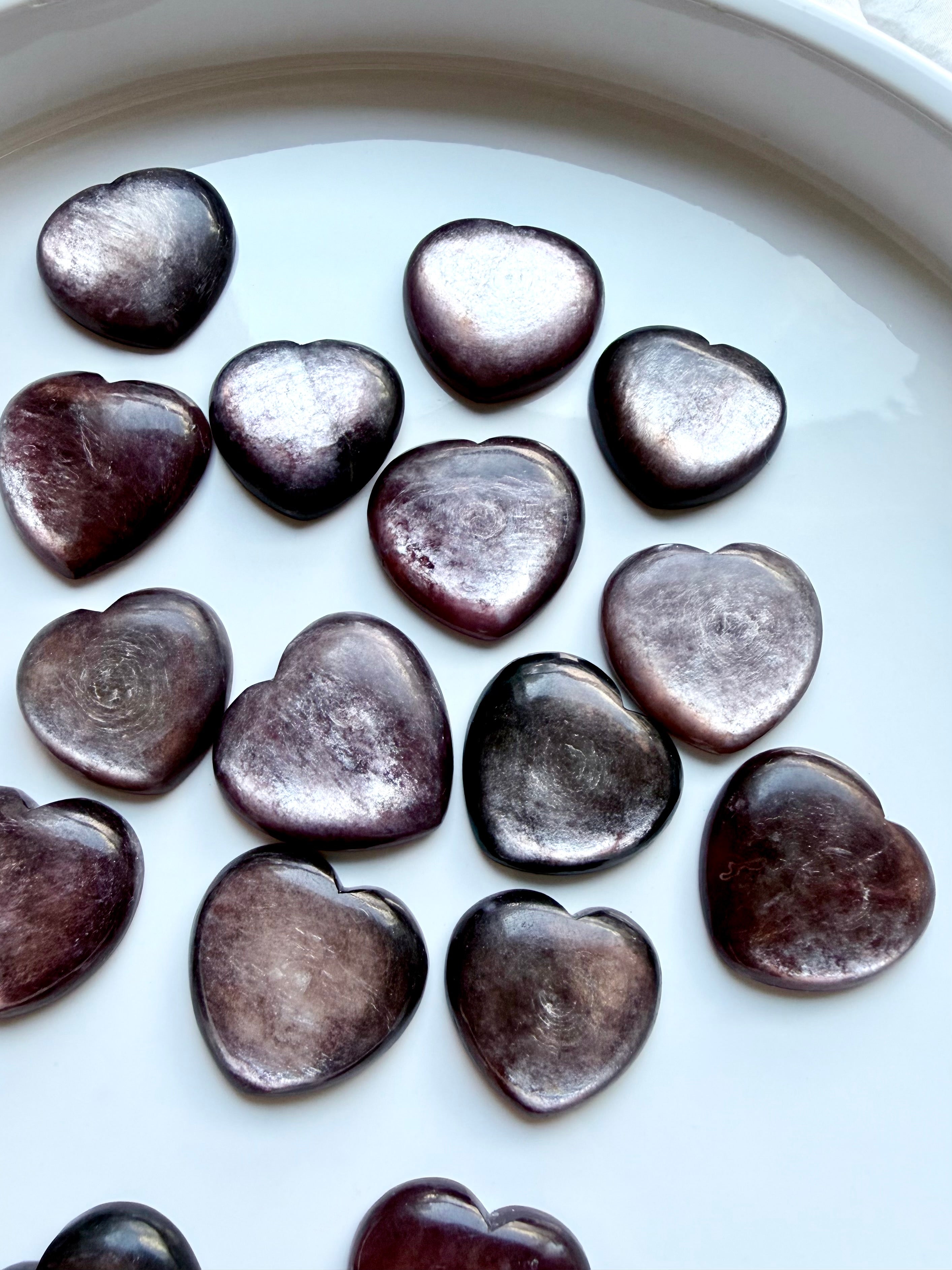 Collection of lepidolite crystal hearts on display tray, polished purple stones for stress relief and balance