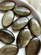 Polished Golden Sheen Obsidian palm stones showing shifting metallic shimmer for Solar Plexus Chakra and personal power