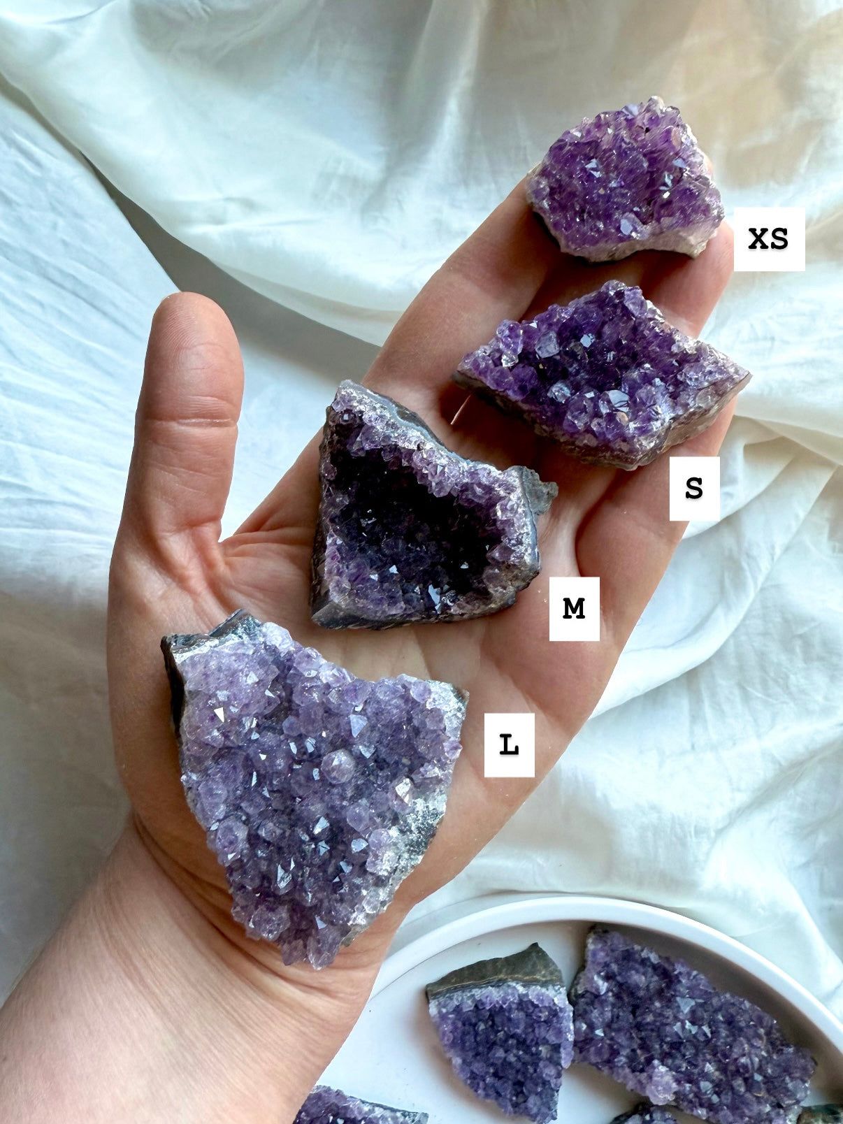 Amethyst crystal clusters XS to Large shown in hand with size labels