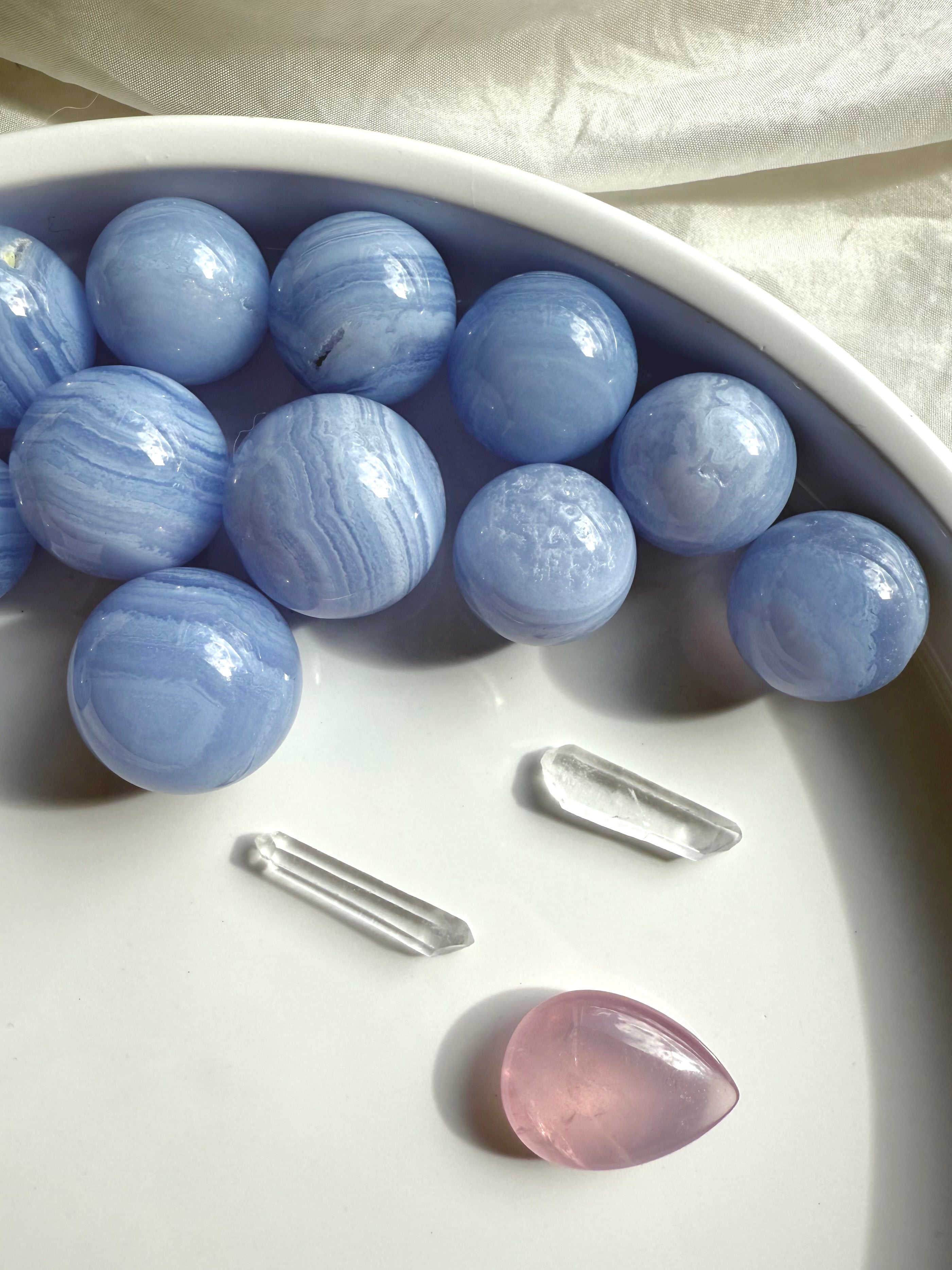 High quality mini Blue Lace Agate Spheres photographed on a white plate in natural light 