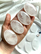 Clear Quartz palm stones held in hand showing translucent clarity, natural white veils and unique internal crystal landscapes