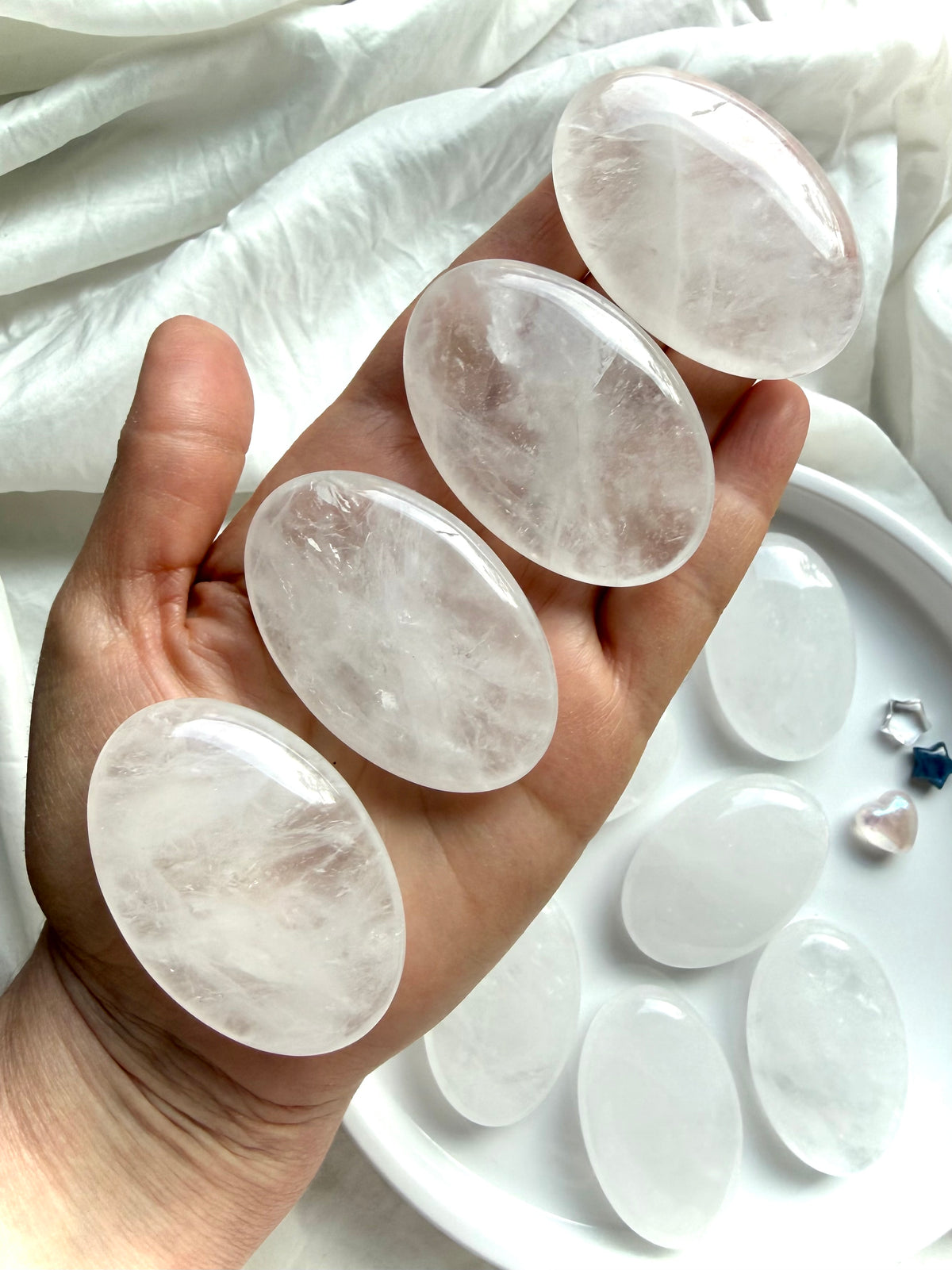 Clear Quartz palm stones held in hand showing translucent clarity, natural white veils and unique internal crystal landscapes