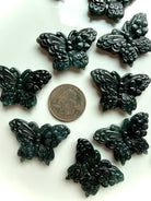Wuji jade butterfly carvings shown with a US quarter for size reference in Guatemalan jade