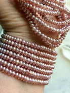 stacked pink freshwater pearl bracelets on wrist, layered pearl jewelry for love, elegance, and heart chakra healing