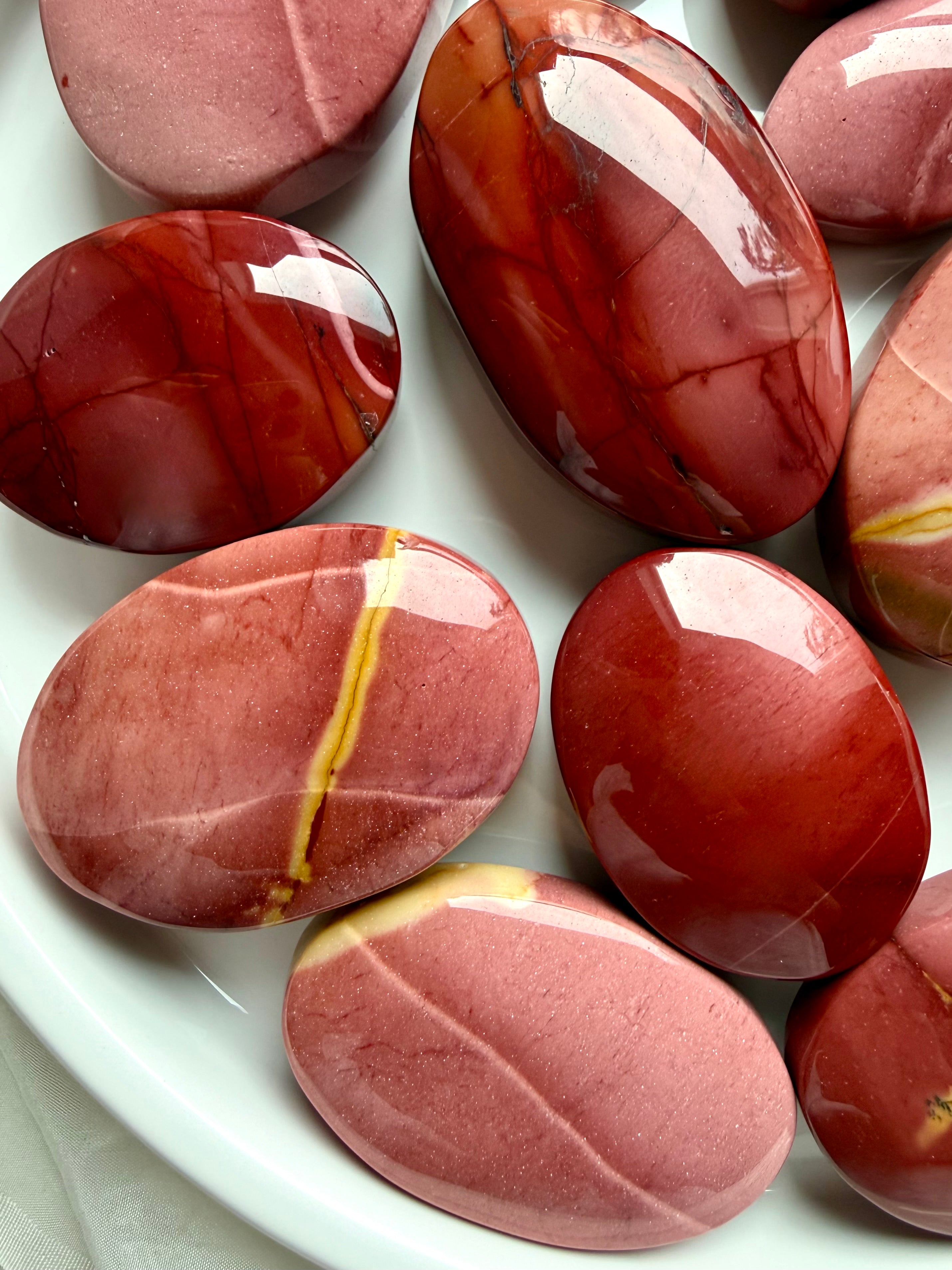 Mookaite Jasper palm stones displayed in ceramic bowl with smooth polished finish and natural earthy color variation