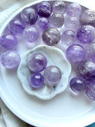 smoky amethyst mini spheres arranged on white tray with marble dish small crystal balls in soft purple tones
