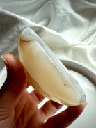 White Agate crystal bowl side view held in hand – polished offering dish for peace, chakra balance, and altar rituals