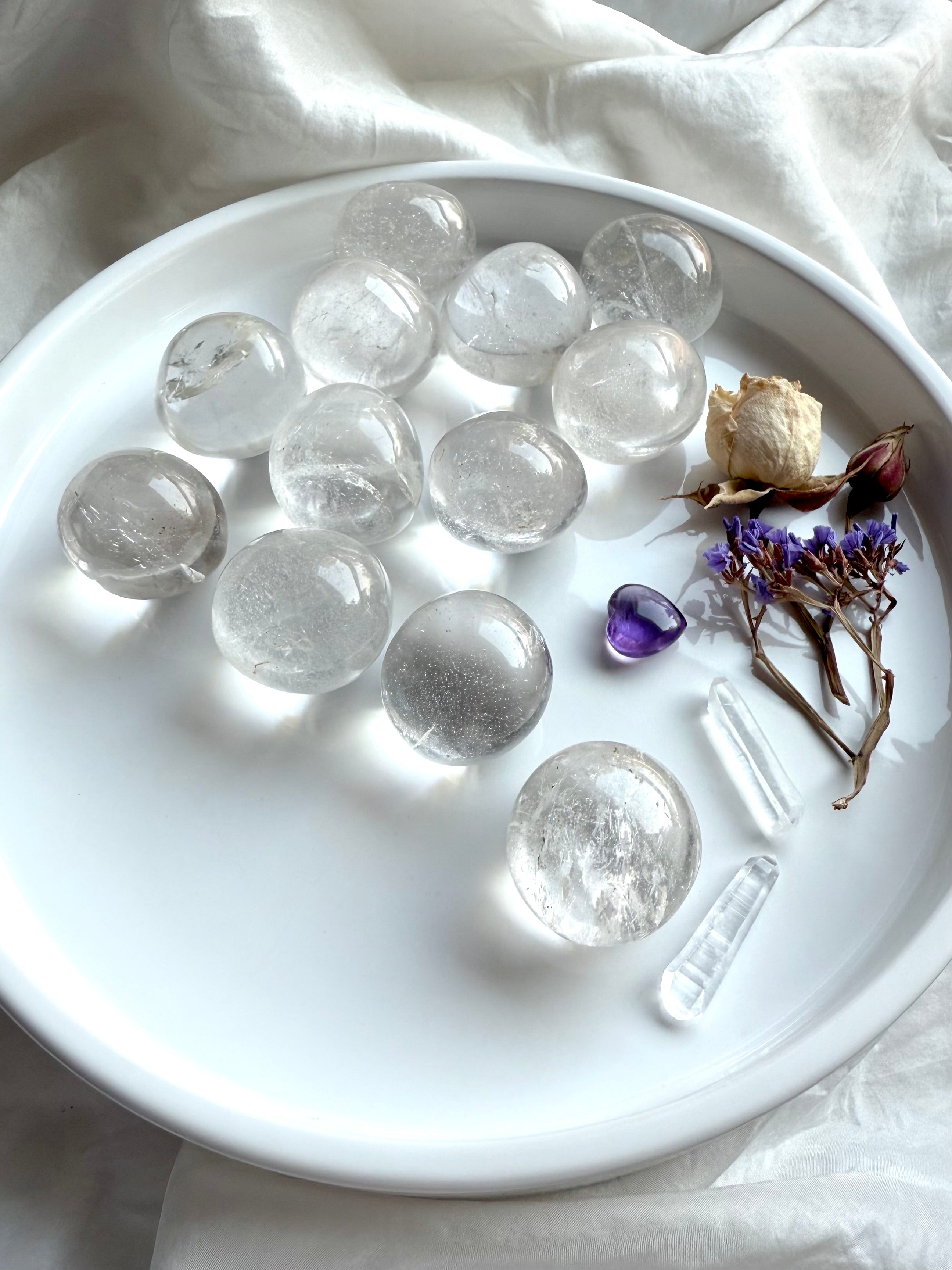High-quality Clear Quartz tumbles on a white ceramic plate, showing luminous clarity and polished finish