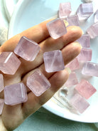 Rose quartz mini cube crystals held in hand with additional cubes in the background, polished heart chakra stones from Mozambique