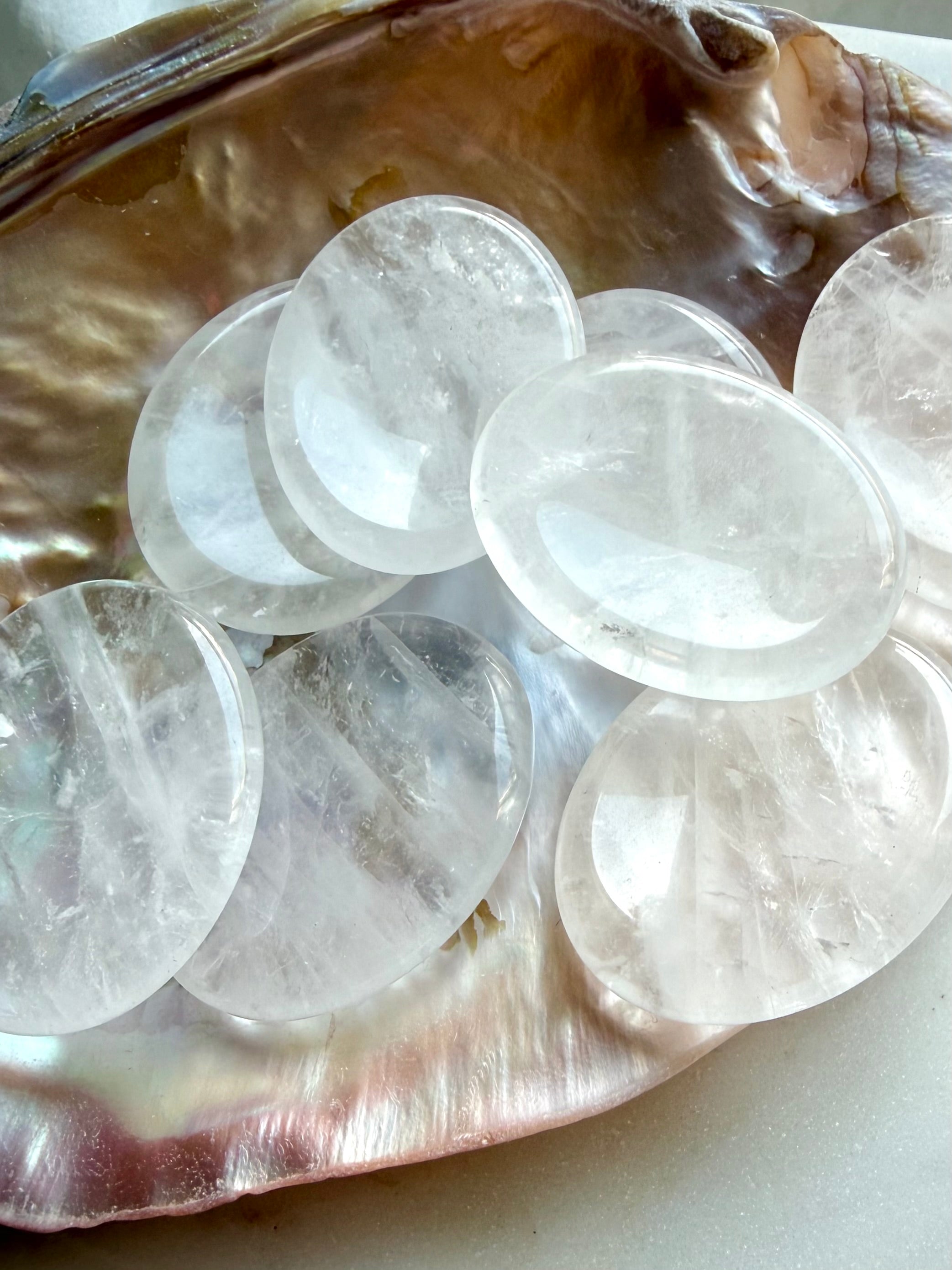 clear quartz worry stones grouped on shell dish for meditation clarity and energy amplification