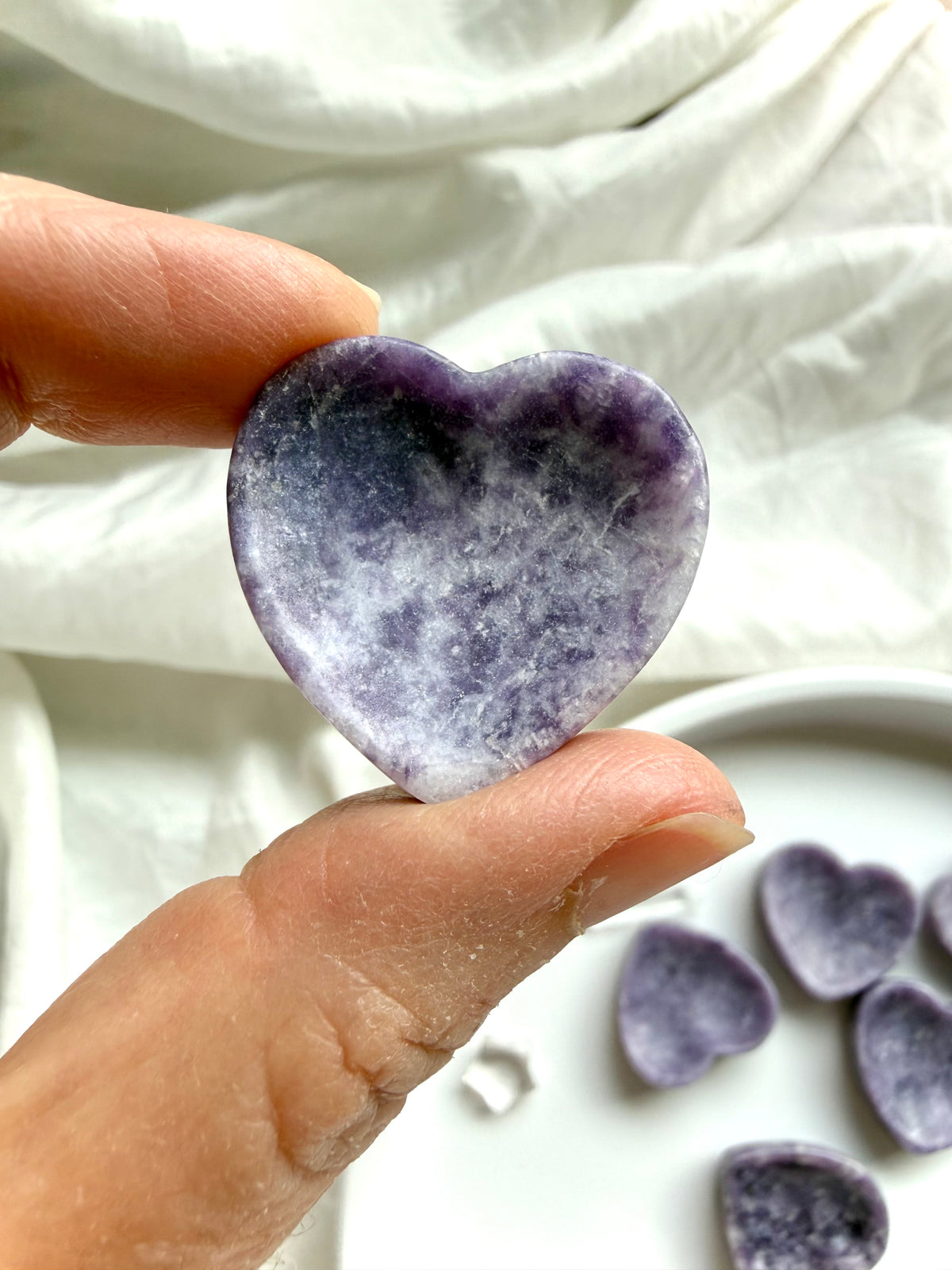 Lepidolite heart bowl held between fingers showing purple mottled patterns, polished finish and miniature jewelry dish size