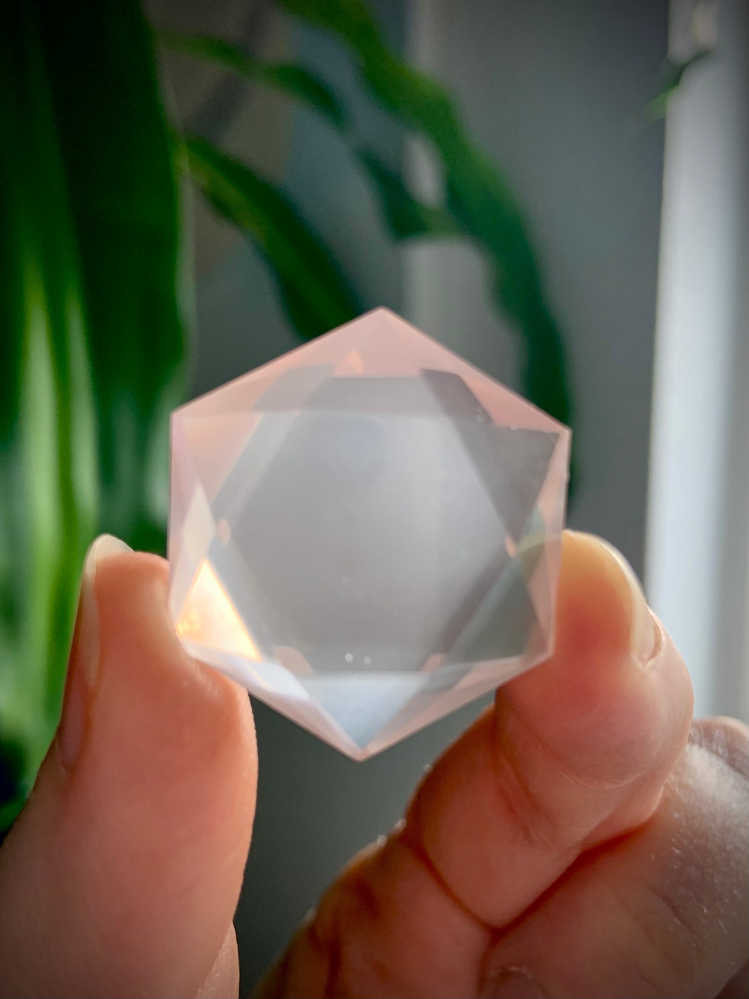 Faceted Rose Quartz hexagon crystal held to the light, glowing translucent pink sacred geometry gem for Heart Chakra love and clarity