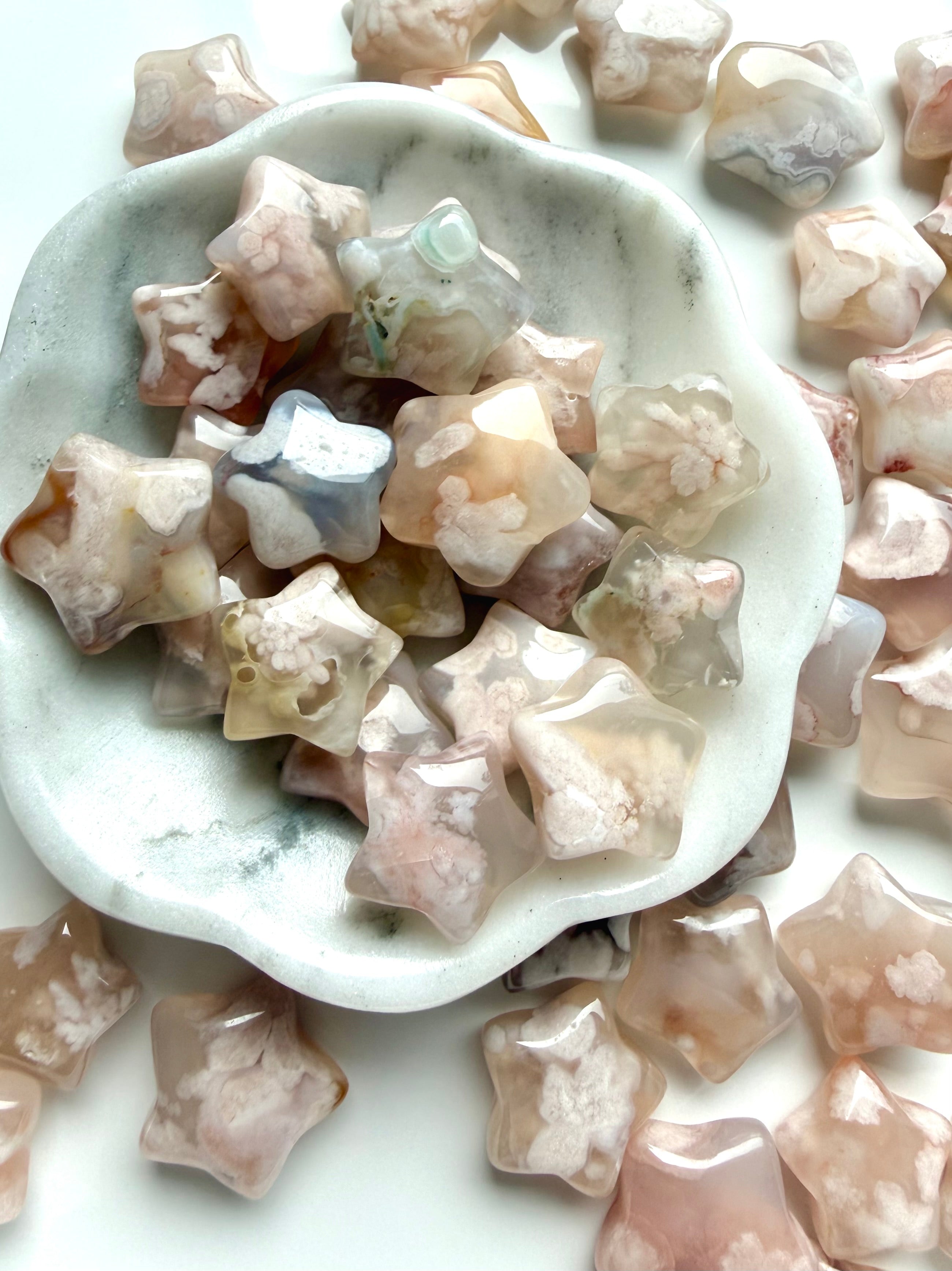 Mini Flower Agate star carvings in soft pink and cream tones displayed in a marble bowl