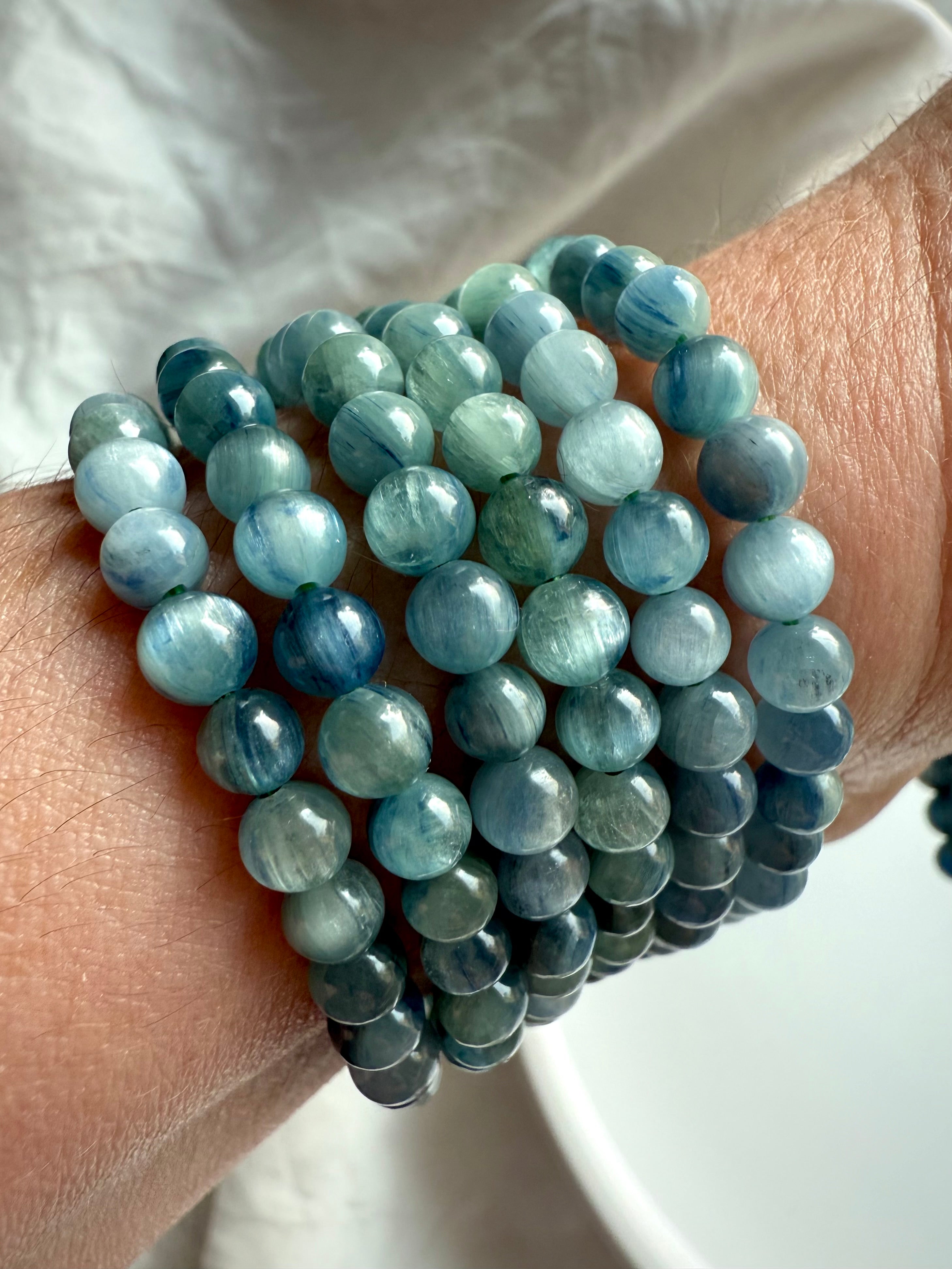 side view of blue-green kyanite bracelets on wrist highlighting the soft glow and metaphysical energy of this throat chakra stone