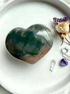Ocean Jasper heart beside crystals and flowers for size reference with polished pastel tones