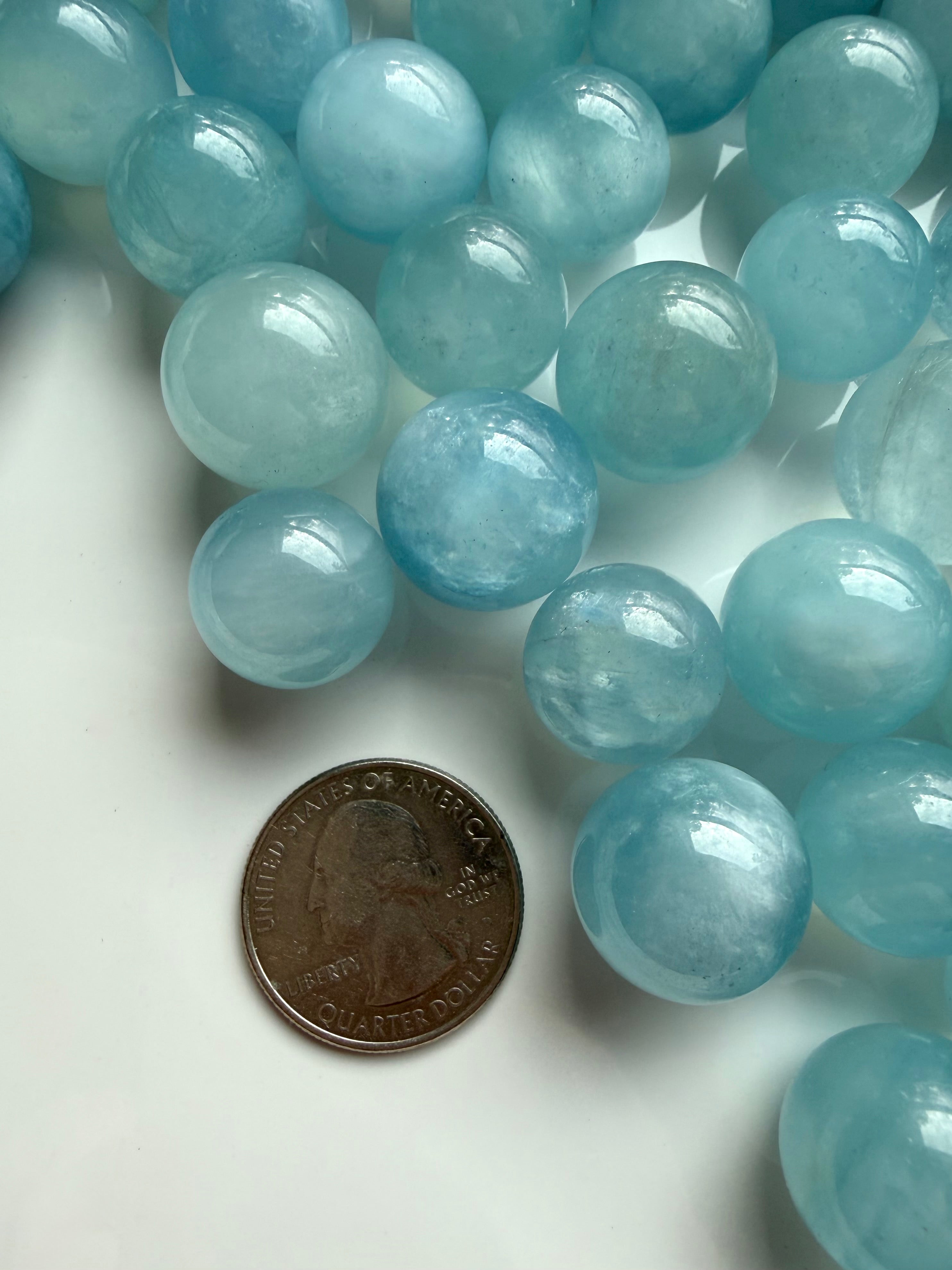 Mini Aquamarine sphere beside coin for scale – small blue March birthstone crystal ball
