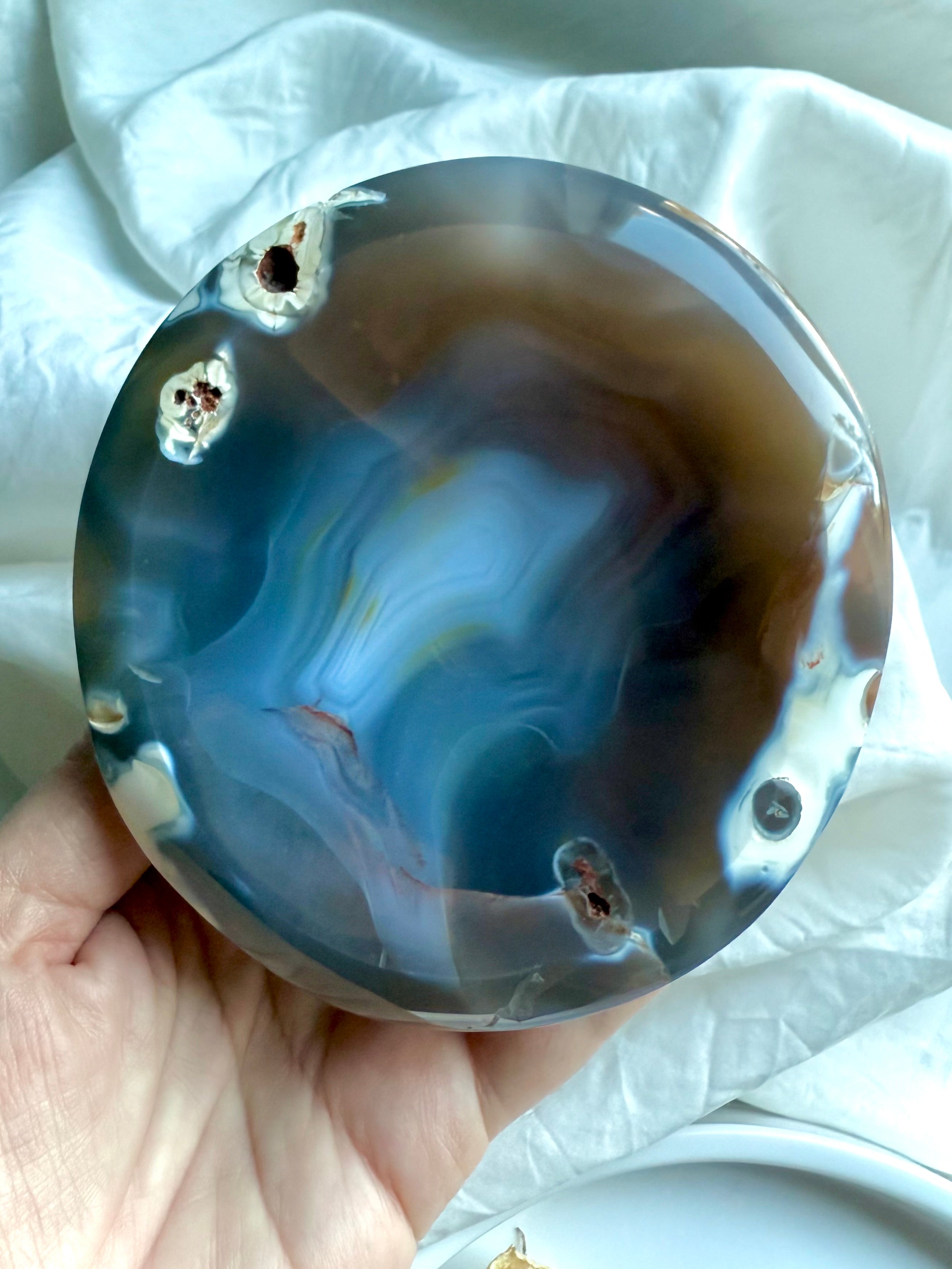 Orca Agate healing bowl held in hand with soft lighting revealing wave-like banding and organic inclusions