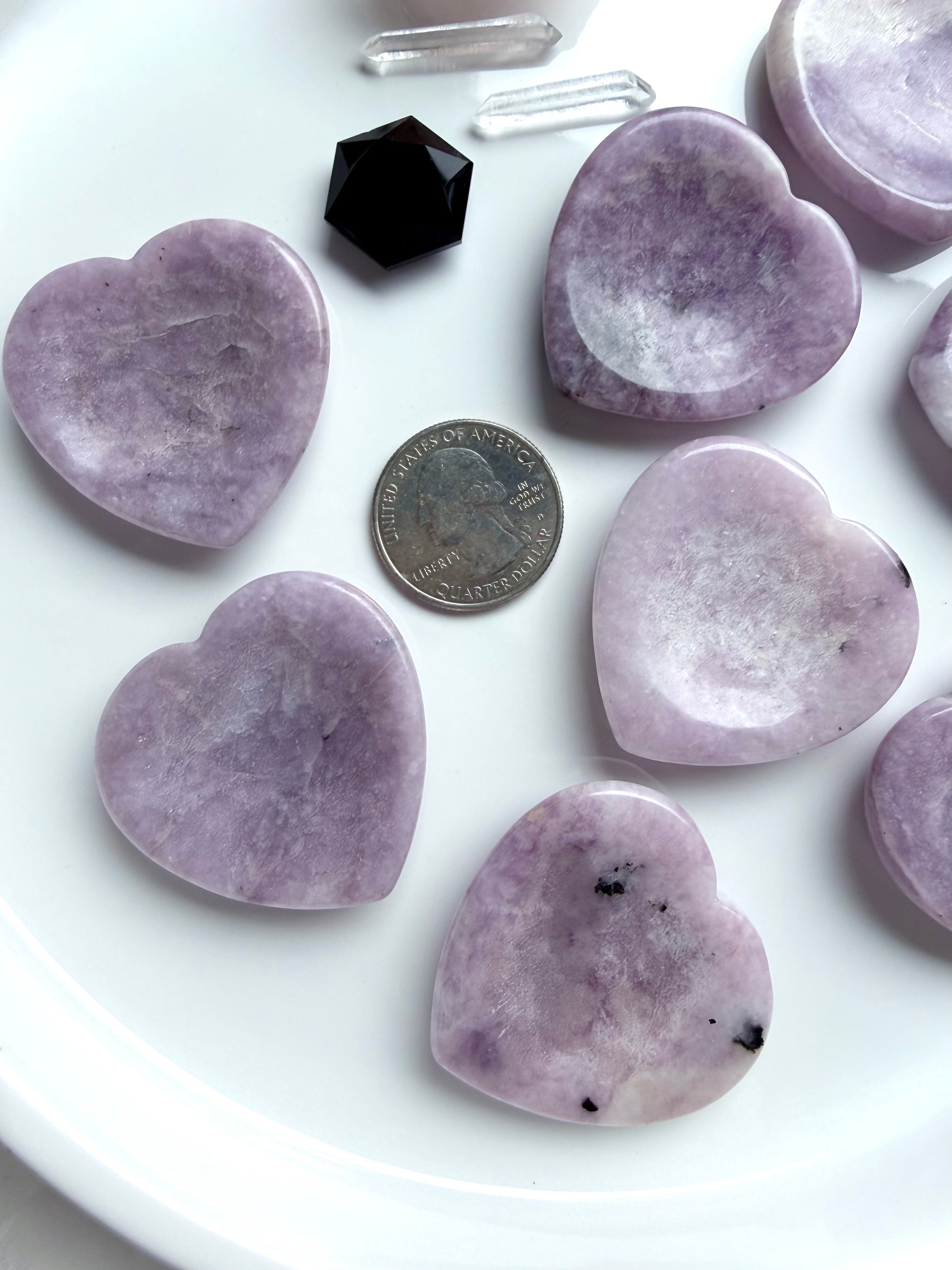 Lepidolite heart worry stones with US quarter for size comparison on white tray