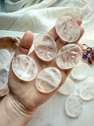 several clear quartz thumb stones in hand for focus clarity and calming energy support