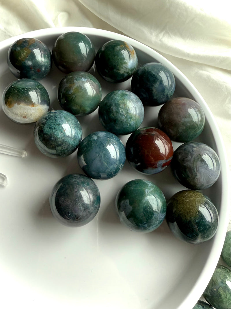 Colorful moss agate mini spheres shown on a white plate, photographed in natural light