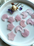Small rose quartz star carvings on a white altar plate with dried flowers and crystals. Heart Chakra crystals for peace, calm, & emotional healing.