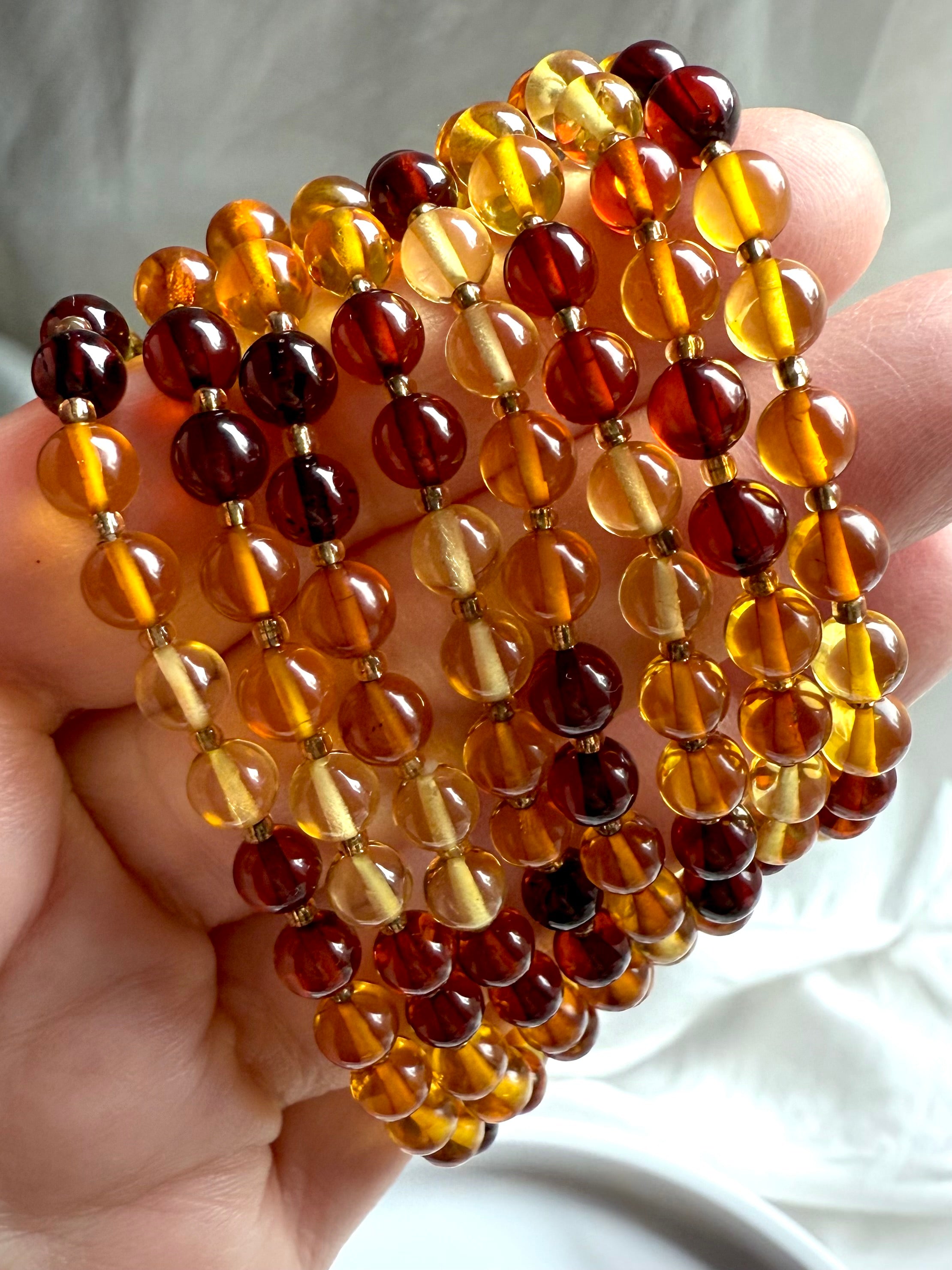 Close-up of multi-tone amber bracelets in sunshine yellow, golden honey + deep cognac – Solar Plexus crystal healing jewelry 