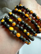 Five stacked bumblebee jasper bracelets laid out in a curved display, glowing yellow hues in radiant orbicular patterns