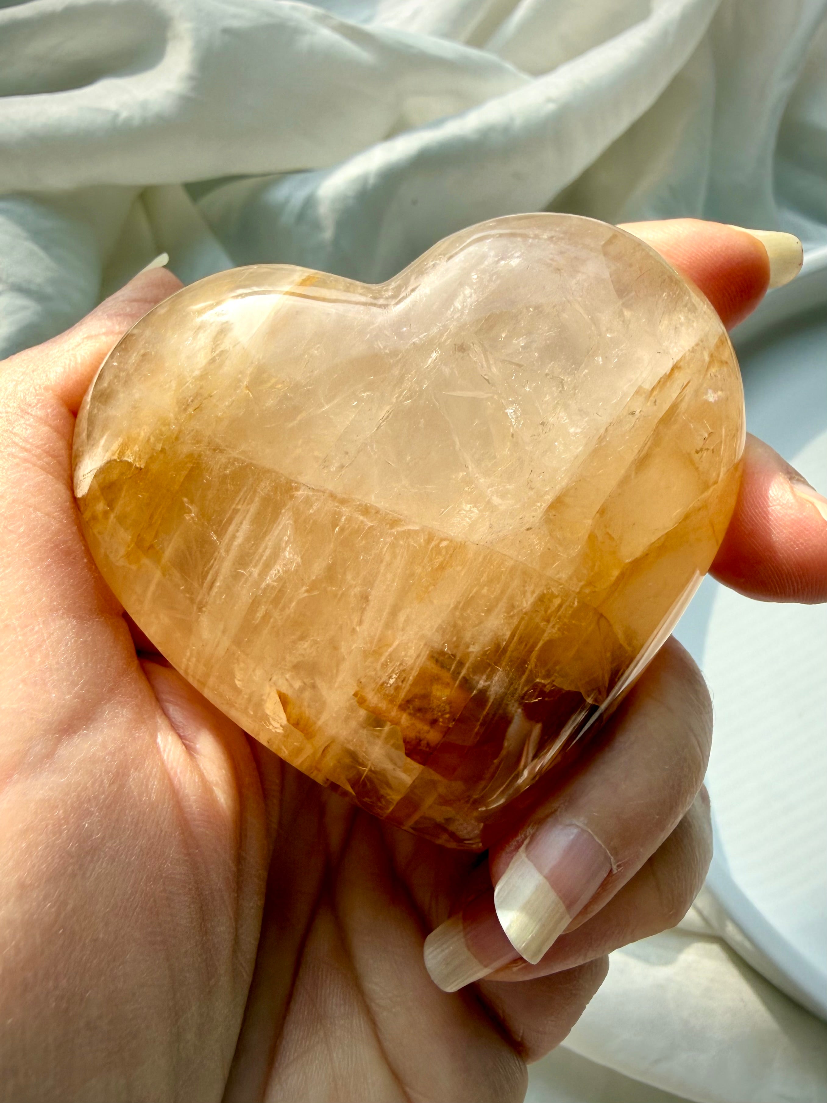 Golden Healer quartz heart held in hand showing honey gold iron inclusions and translucent clarity for Solar Plexus empowerment