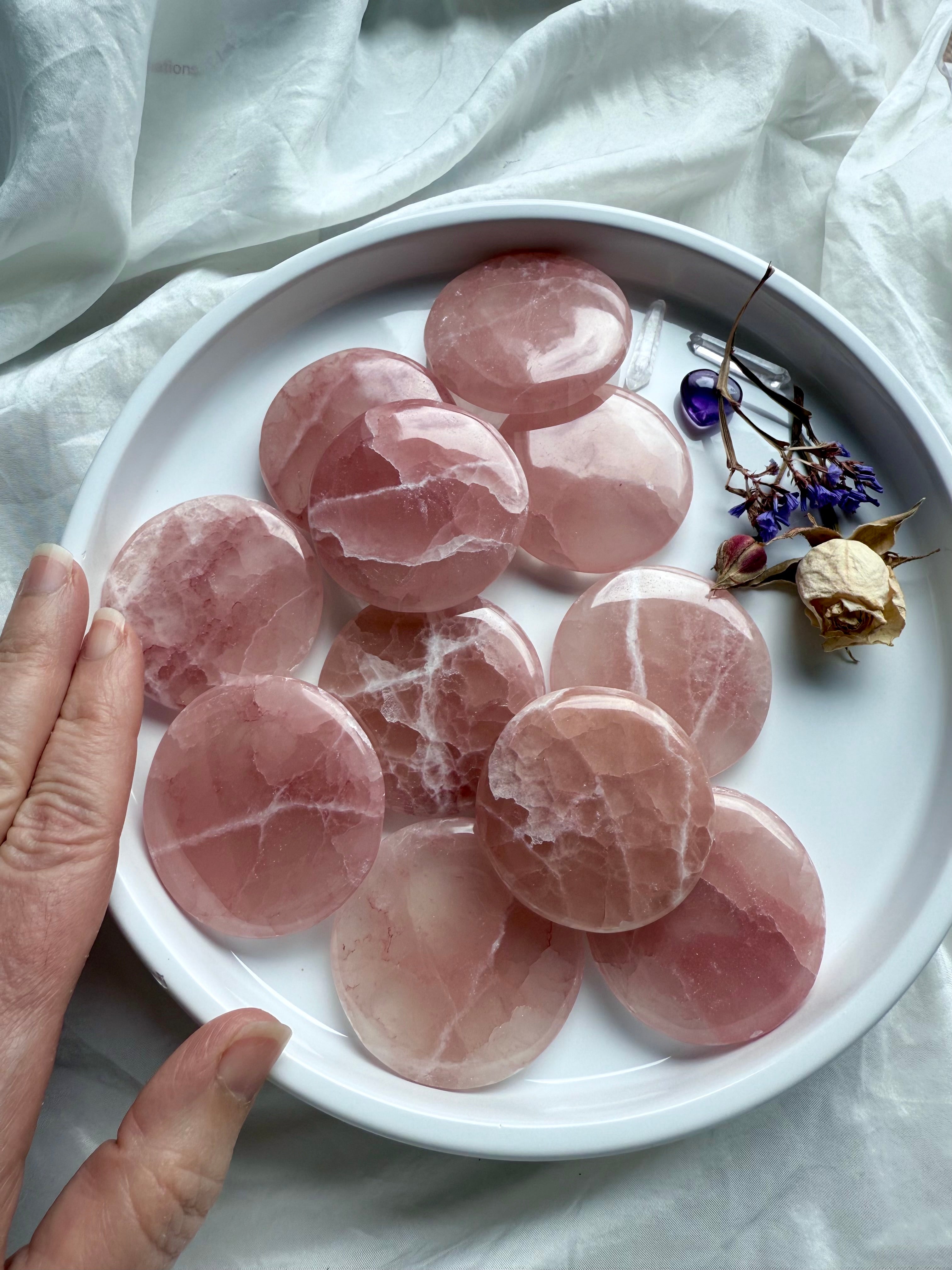 Group of Rose Calcite discs with swirling white patterns and blush pink tones shown in a shallow crystal offering bowl