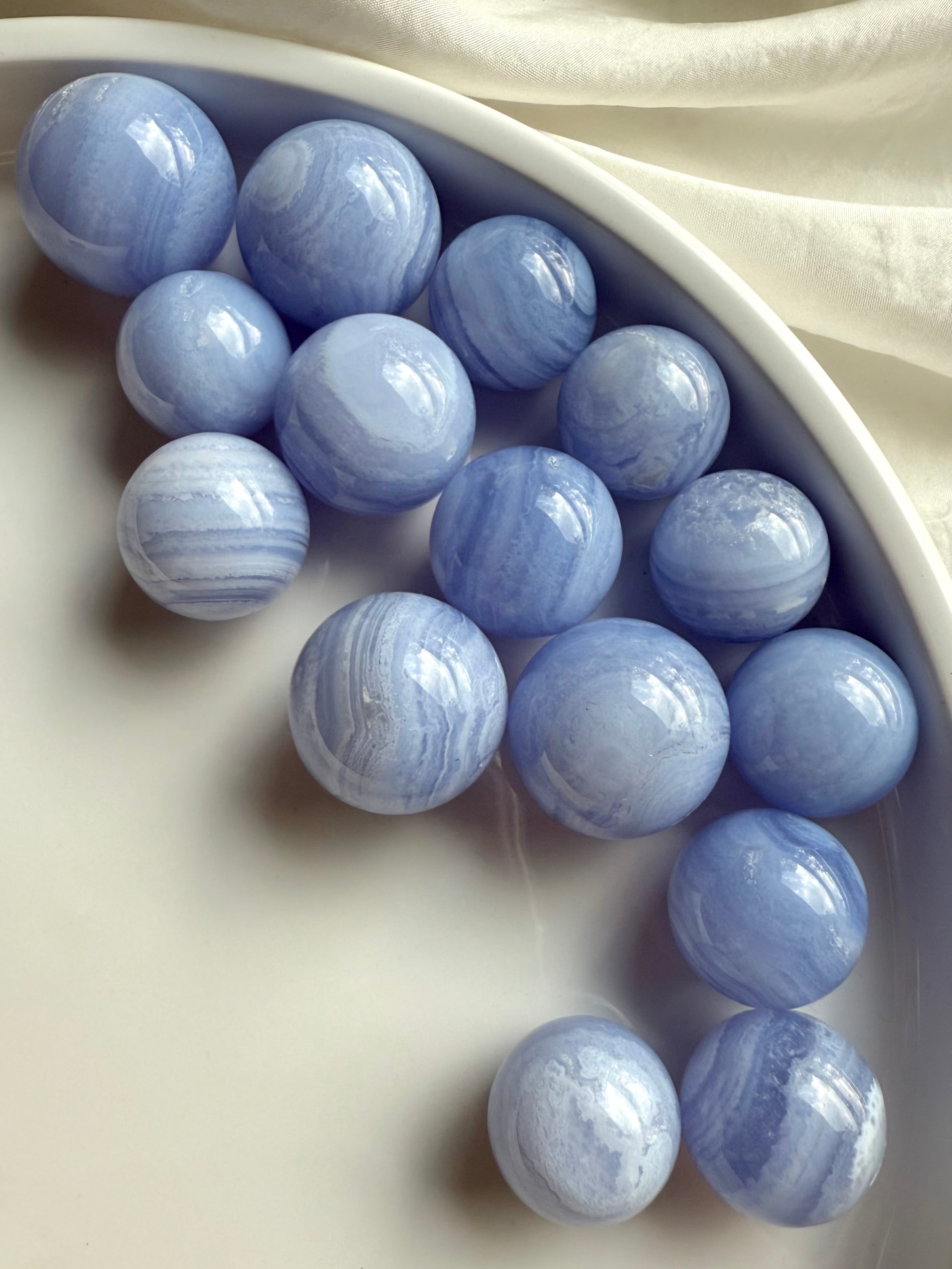 An array of mini sized high quality Blue Lace Agate Spheres on a white plate