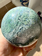 Moss Agate sphere close up showing detailed green moss patterns, Quartz pockets, and polished finish