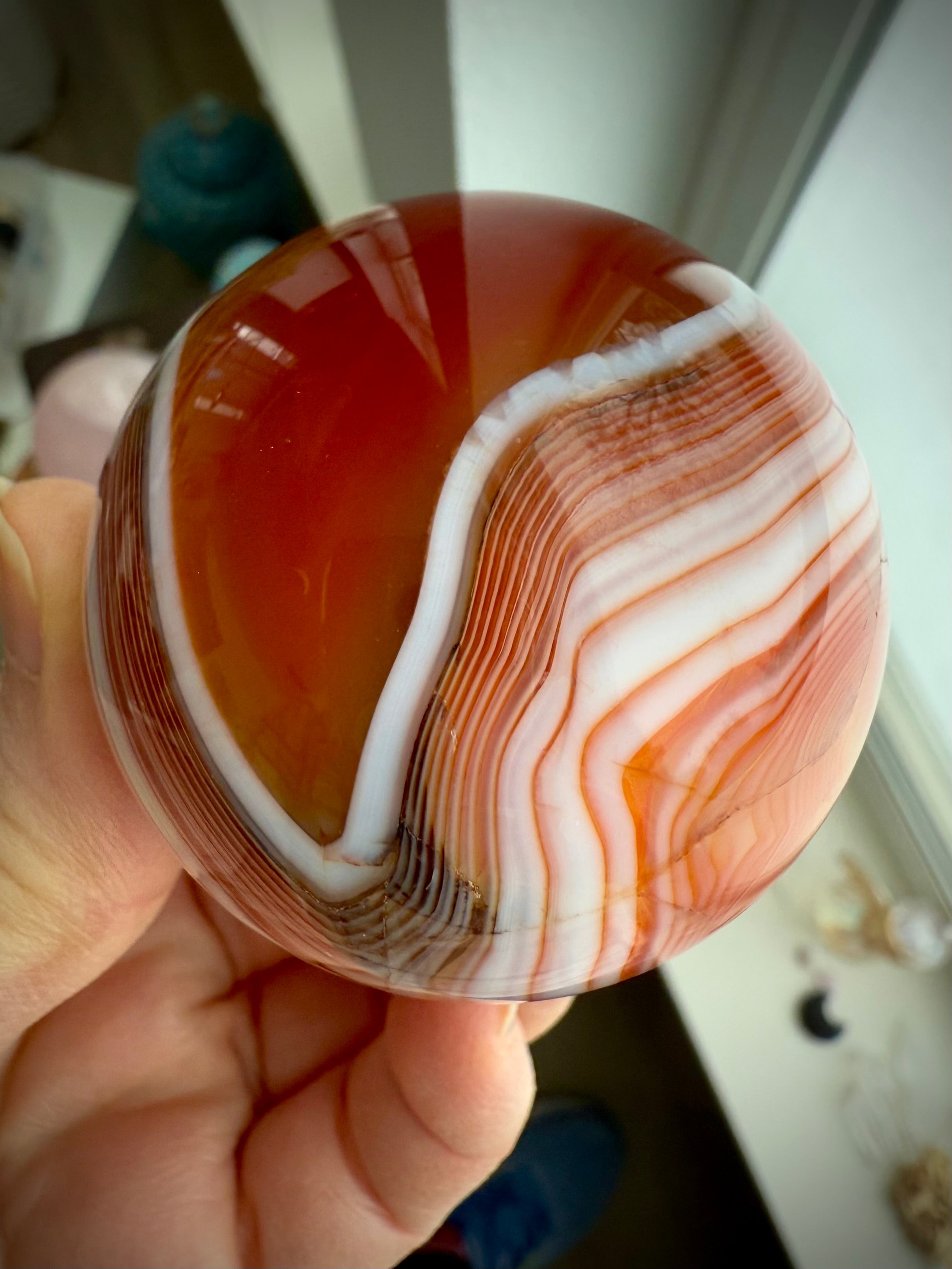 A banded carnelian crystal ball with an intricate chevron pattern swirling around the sphere