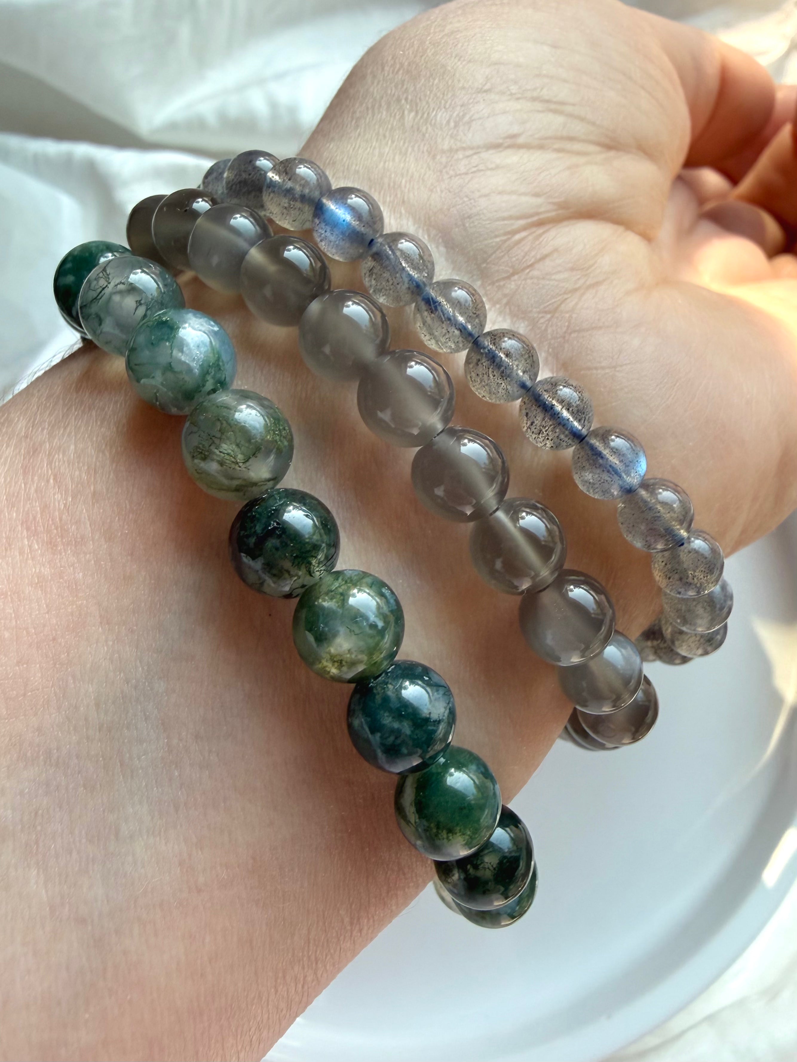 Labradorite, Black Moonstone, and Moss Agate crystal bracelets worn together in a natural gemstone bracelet stack