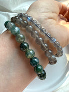 Labradorite, Black Moonstone, and Moss Agate crystal bracelets worn together in a natural gemstone bracelet stack