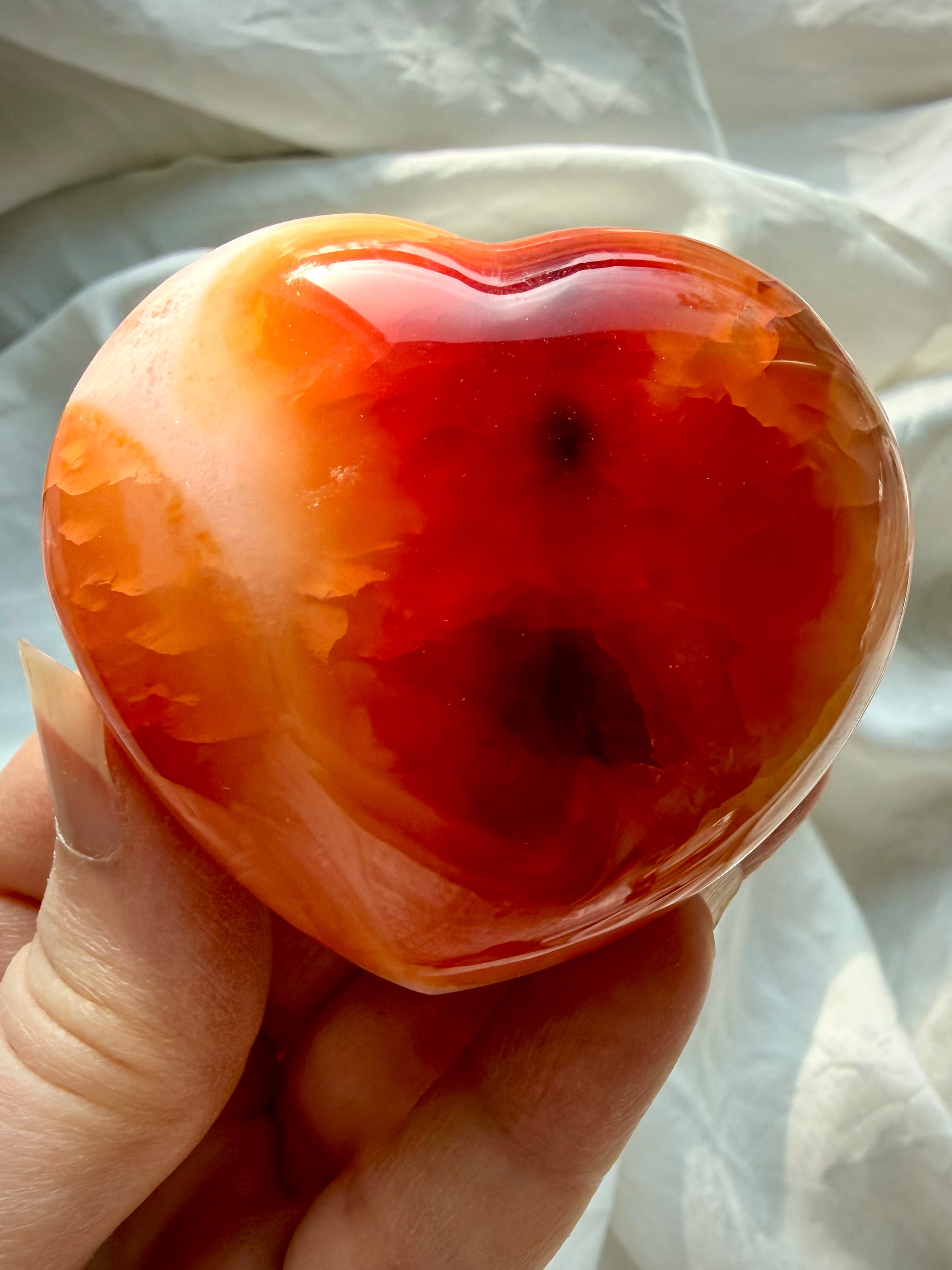Palm size Carnelian heart crystal held in hand, polished Sacral Chakra stone for vitality and empowered action