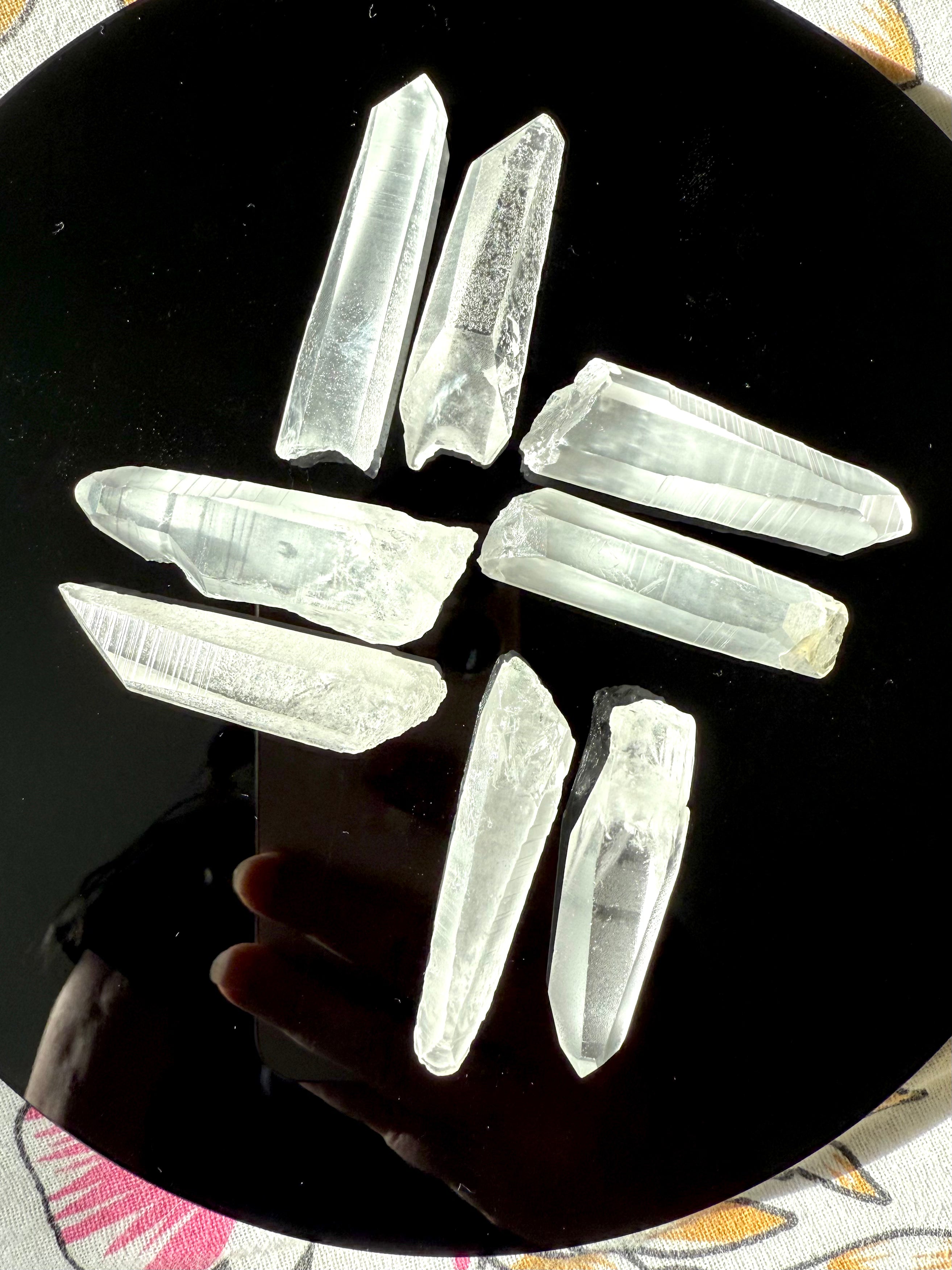 High-vibe Lemurian Quartz points laid out in a geometric grid on an obsidian plate — used for grounding, clarity & ascension work