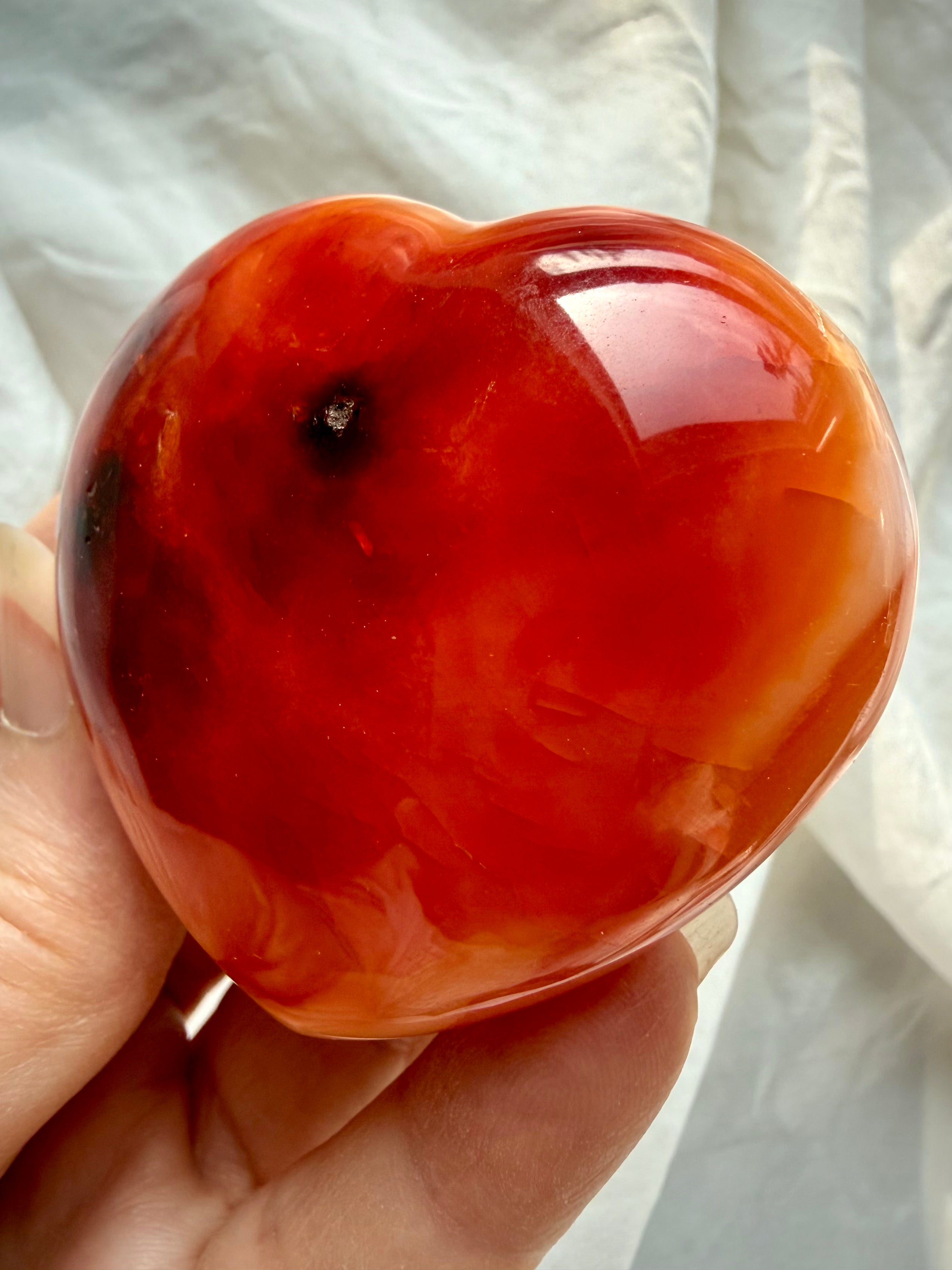 Back view of one of a kind Carnelian heart with sunset orange tones, creamy white patterning, and smooth rounded edges