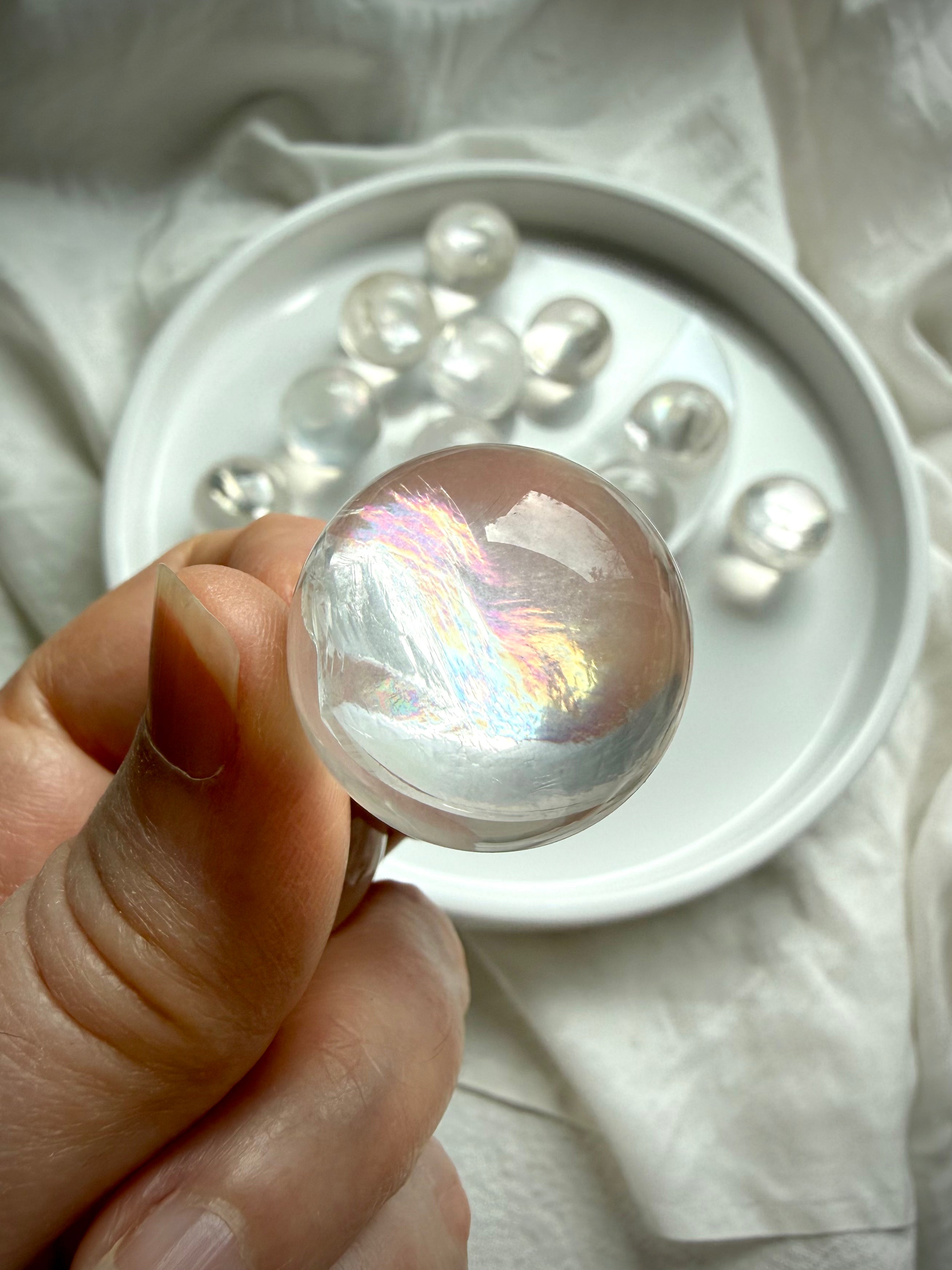 Close-up of rainbow girasol mini quartz sphere with opaline milky translucency and subtle internal rainbow flash