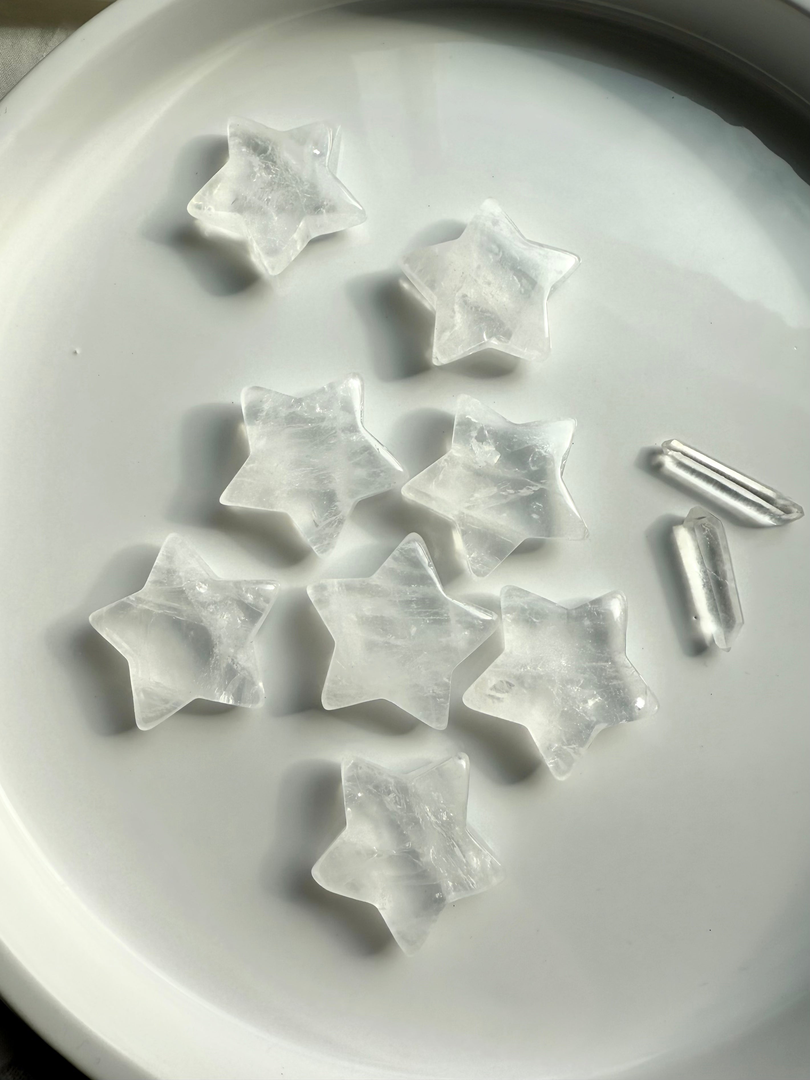 Array of Clear Quartz star carvings on a white plate with quartz points, healing crystals for chakra balance, meditation, and altar décor