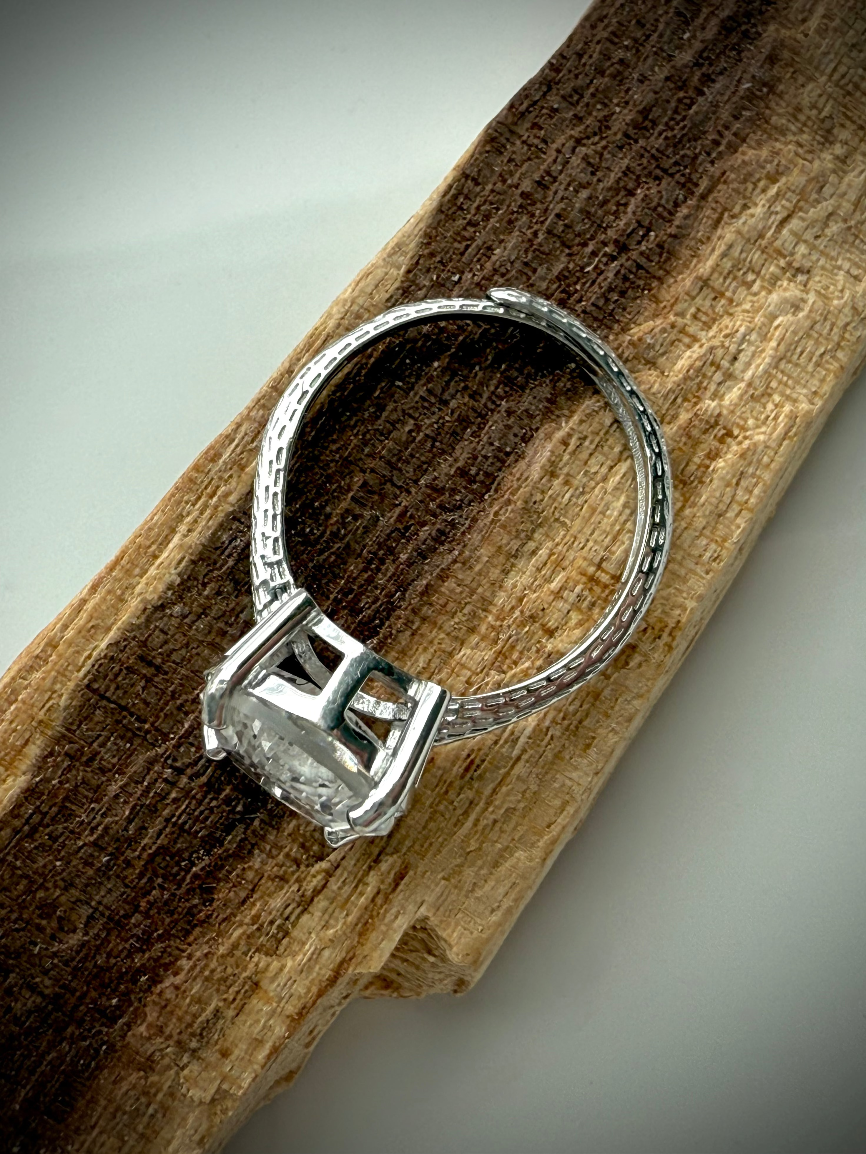 side view of sterling silver moon ring showing details of adjustable band design on wooden surface