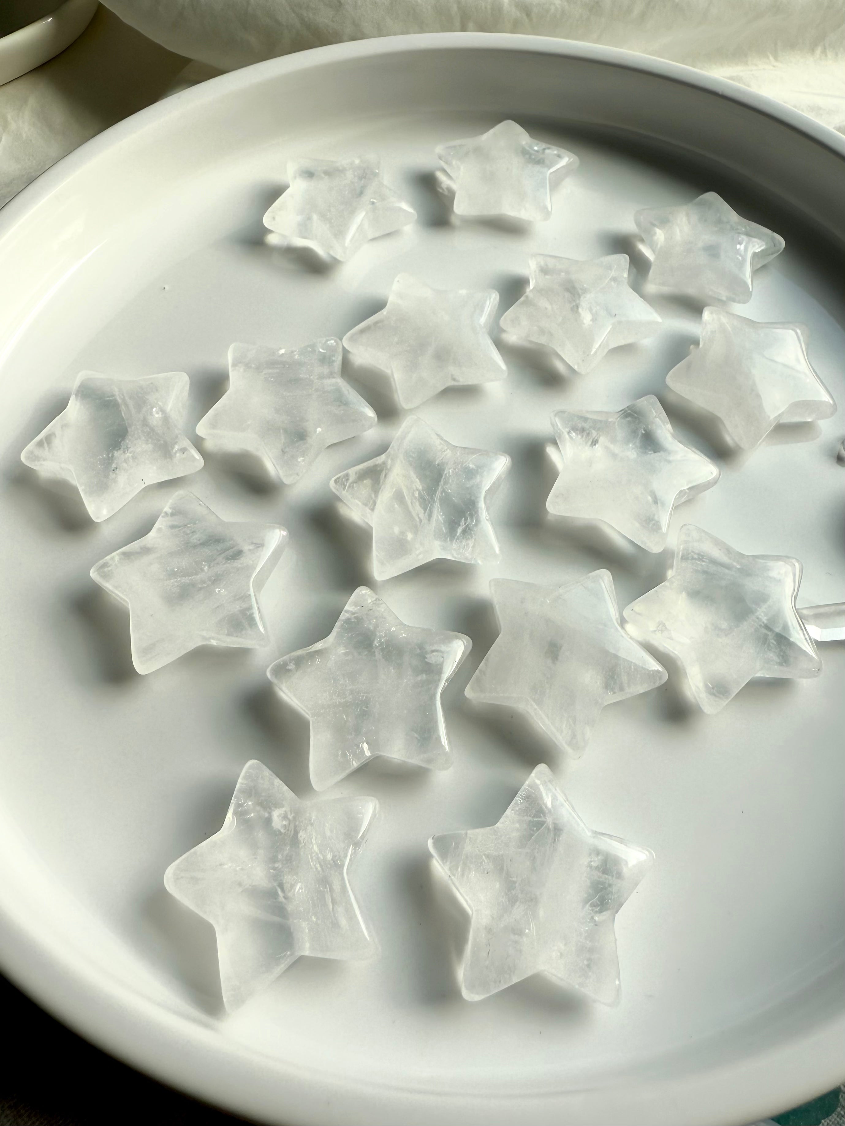 Wide angle view of Clear Quartz star crystals arranged on white plate, celestial carvings for meditation and energy work