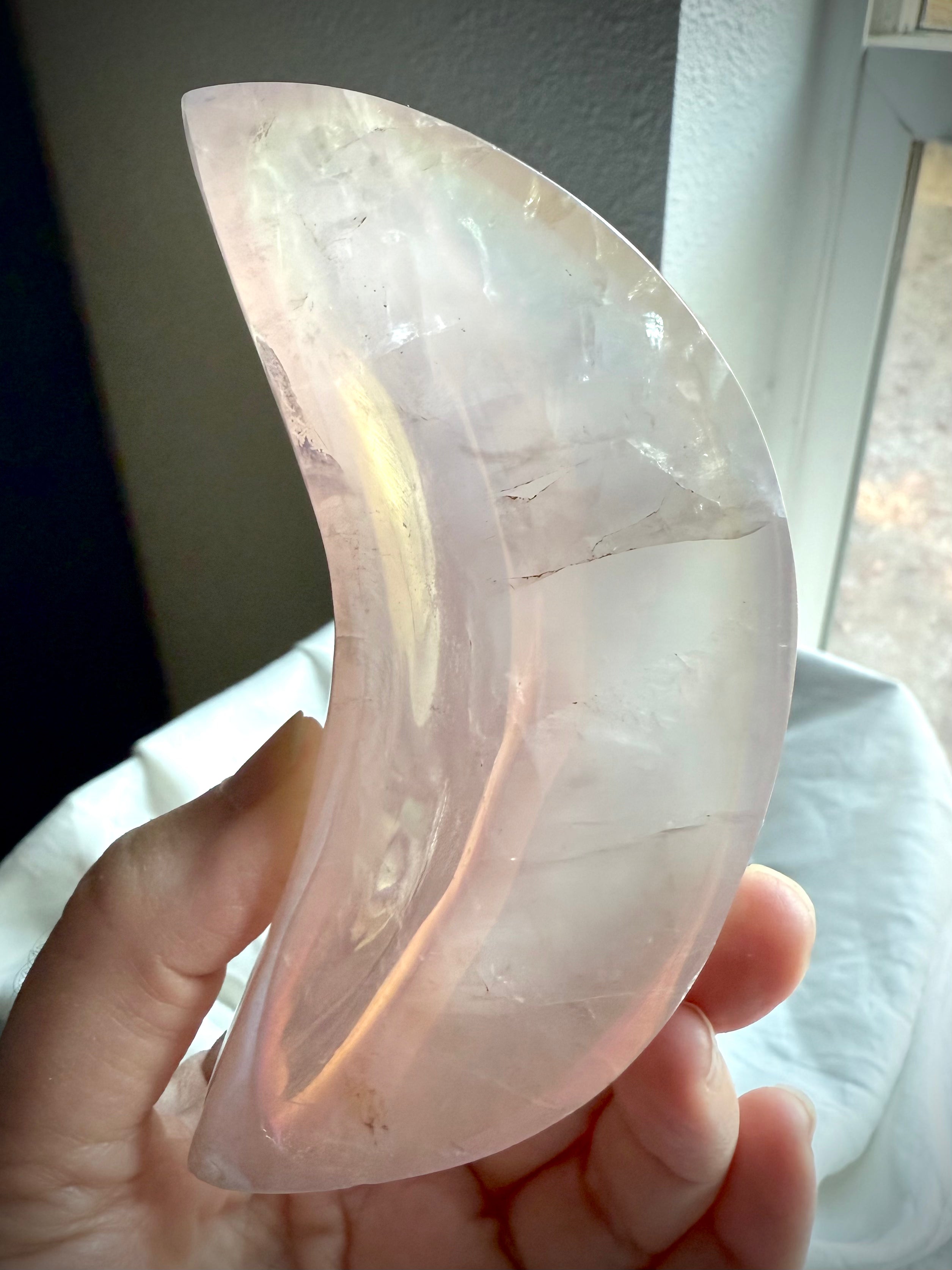 Dreamy pink Aura Rose Quartz crescent bowl held to the light showing the dreamy opalescent pink crystal