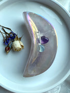 Aura Rose Quartz crescent moon bowl with opalescent lilac shimmer, displayed with dried flowers, mini hearts, and clear quartz points