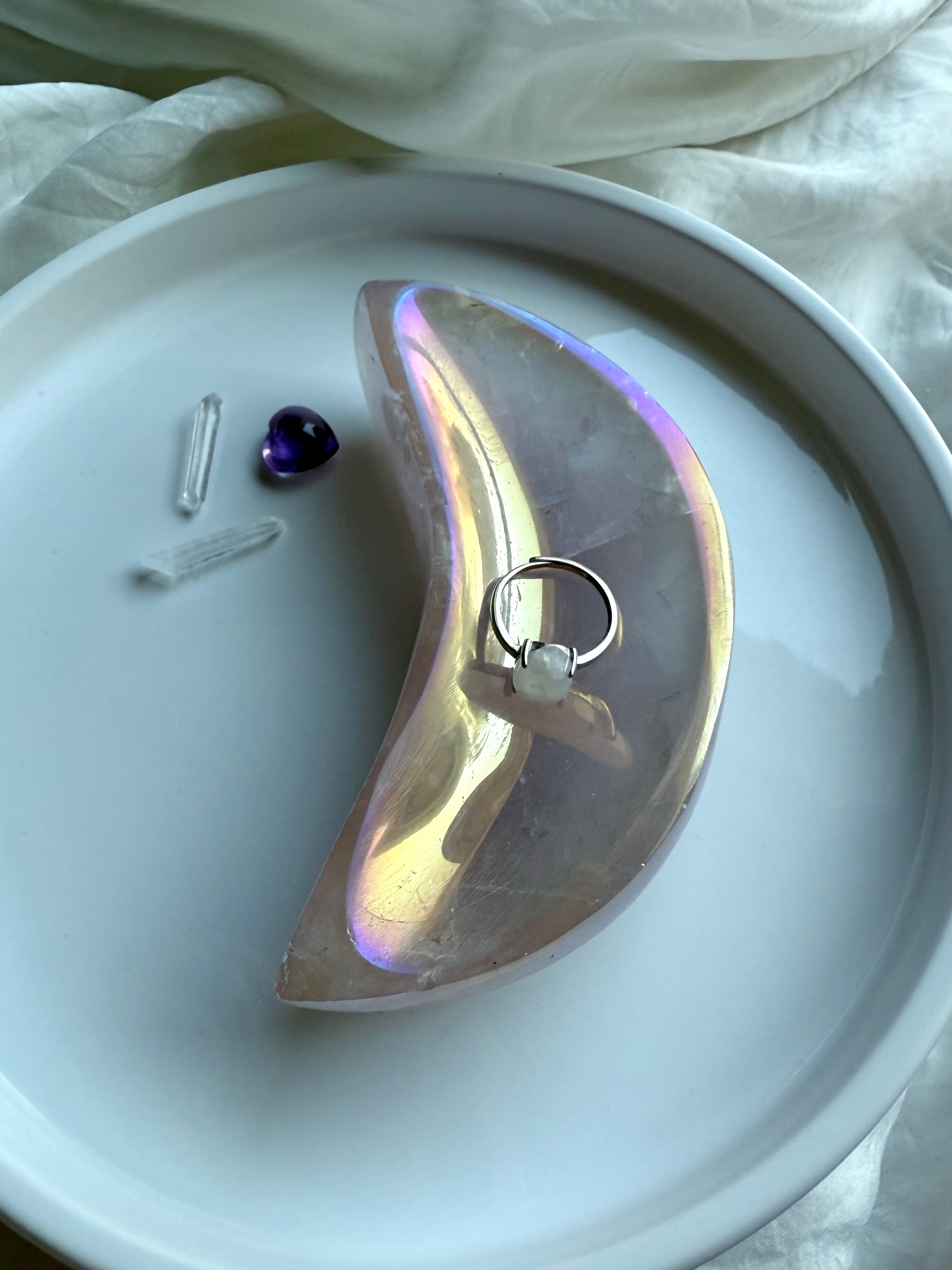 Aura Rose Quartz crescent moon bowl with opalescent lilac shimmer holding a ring