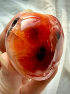 Side view of one of a kind Carnelian heart showing glossy polish, natural druzy cave detail, and raw texture spot on edge