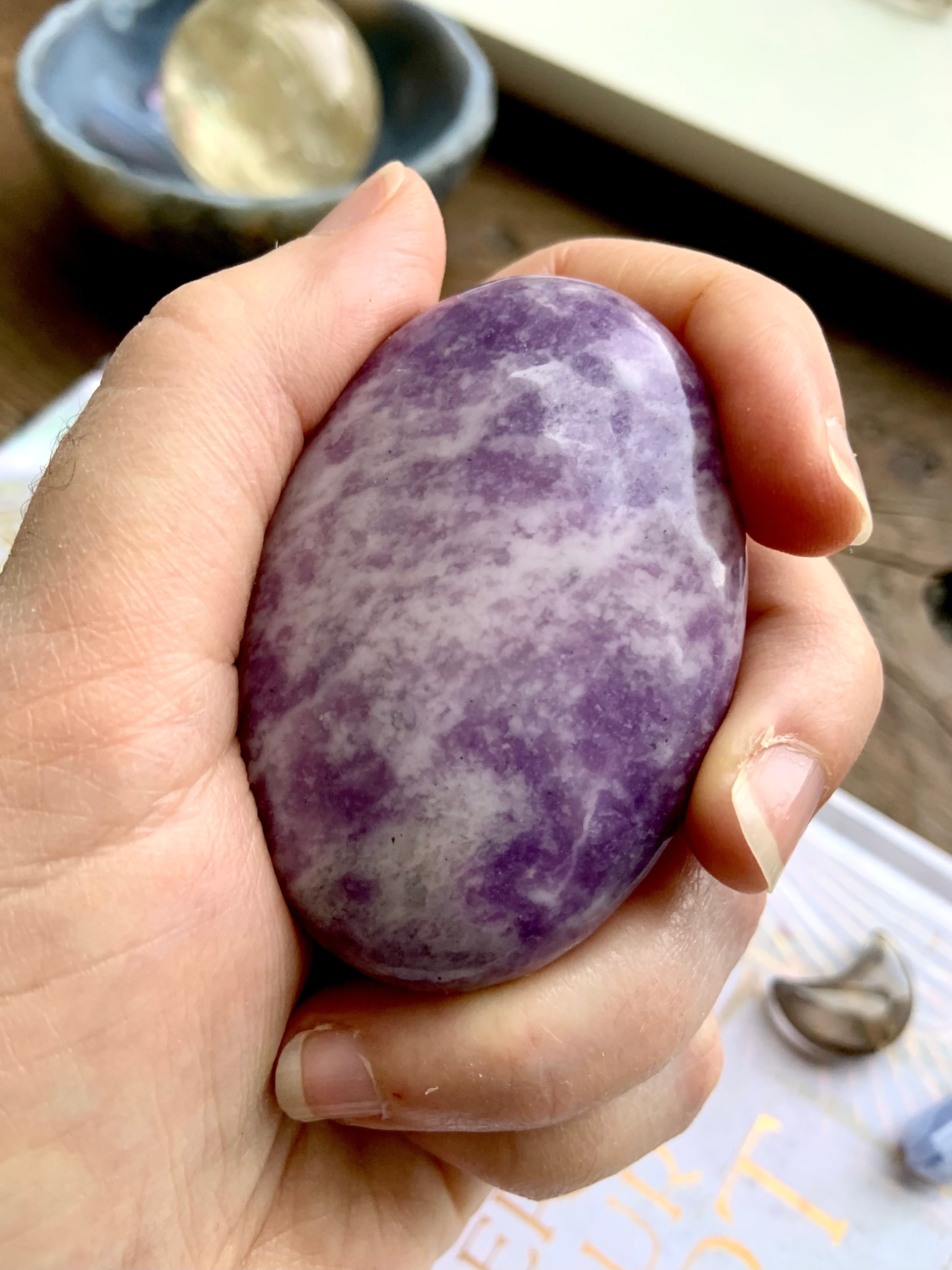 Healing lepidolite palmstone in hand, supportive crystal for peace, calm, and emotional renewal