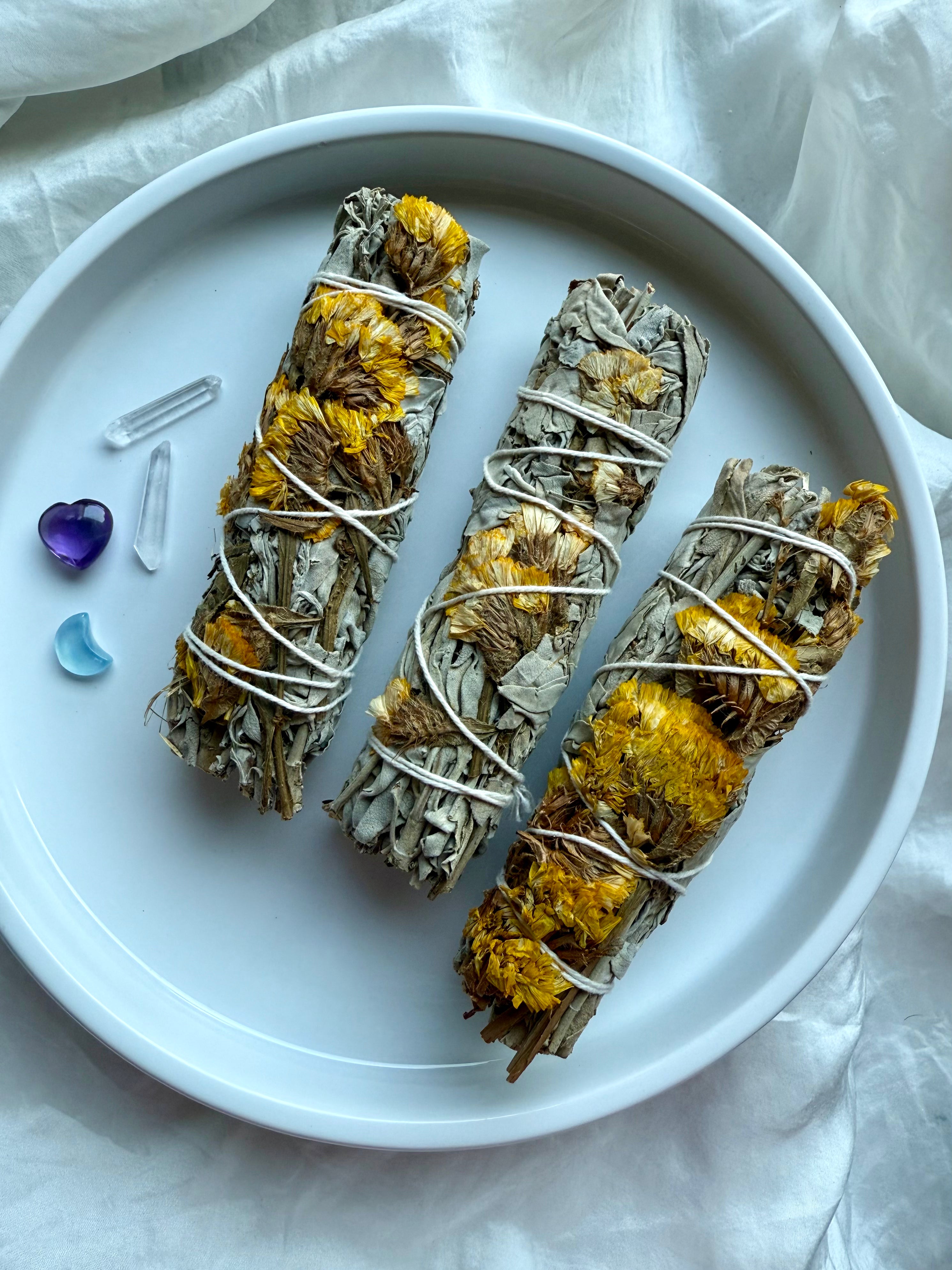 Floral white sage smudge bundles with yellow statice flowers and crystals for cleansing, gifting, and sacred rituals