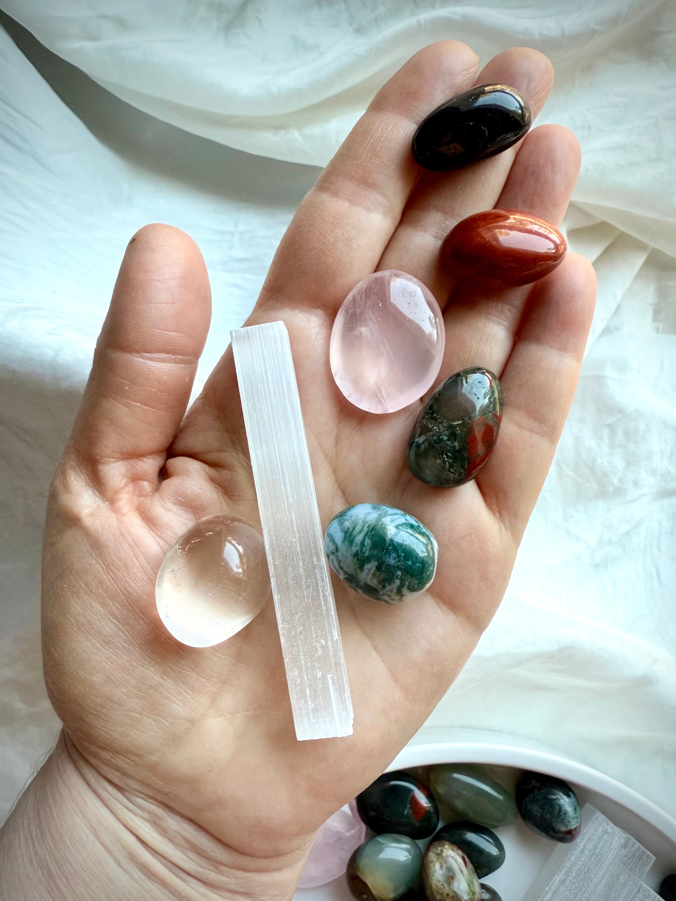 Get Well crystals including Red Jasper, Rose Quartz, and Moss Agate shown in hand for scale